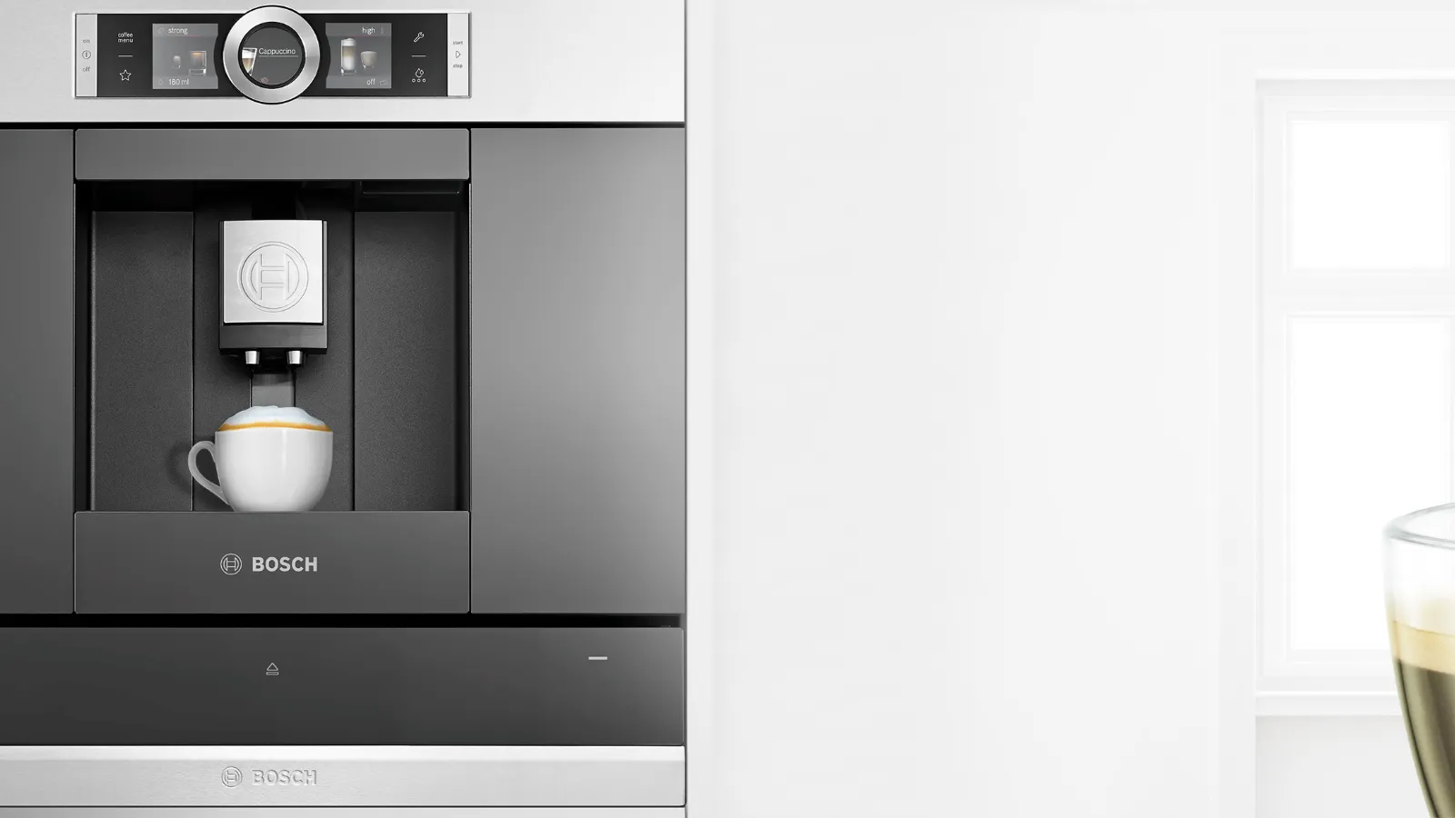 Built-in coffee maker, espresso cup, and bright window in modern kitchen.