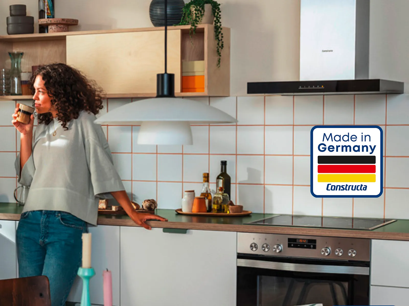 Frau steht in einer Küche, Dunstabzugshaube mit Made in Germany Logo
