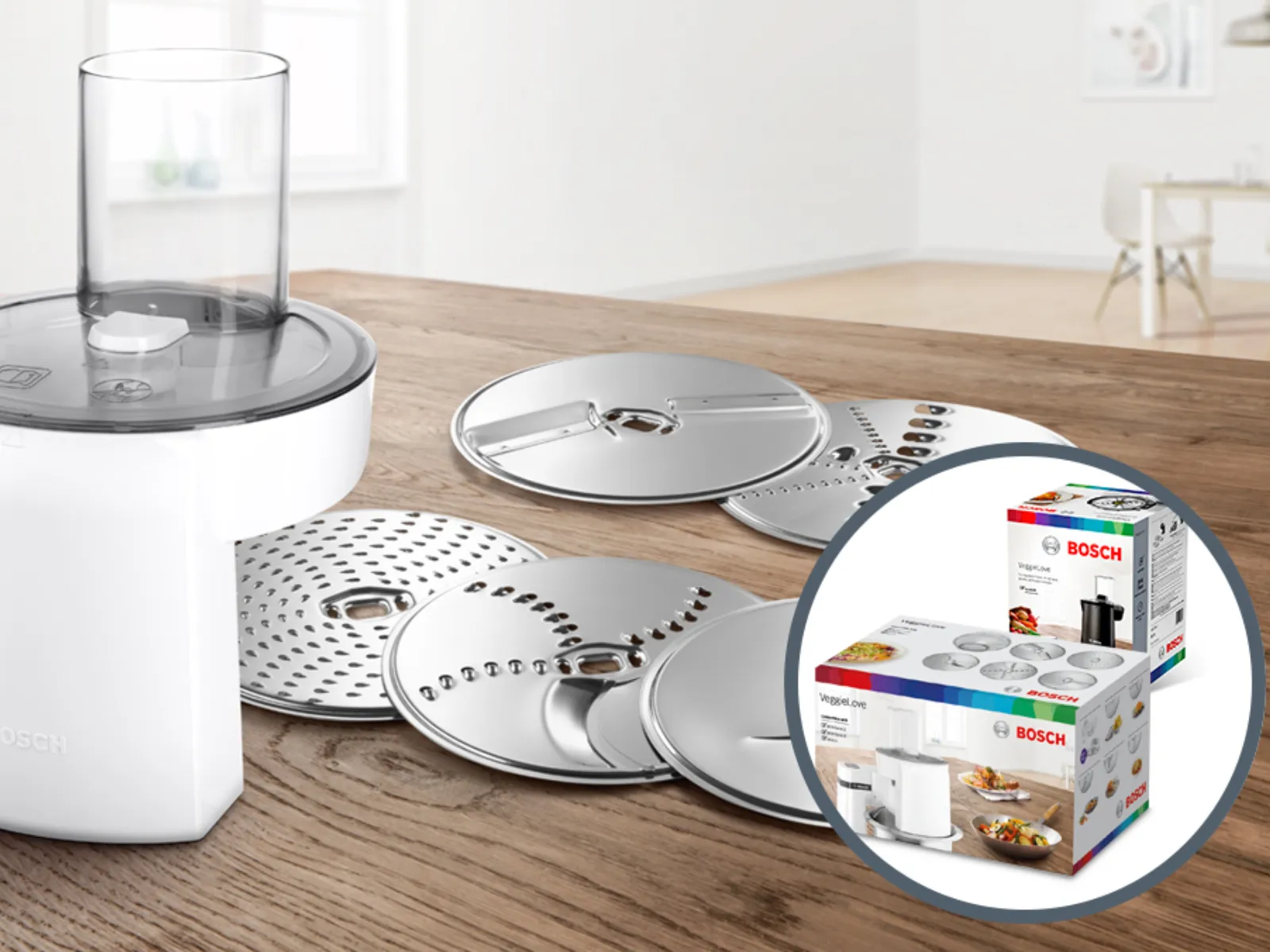 Kitchen appliance with various attachments on wooden table, including fruits and vegetables.