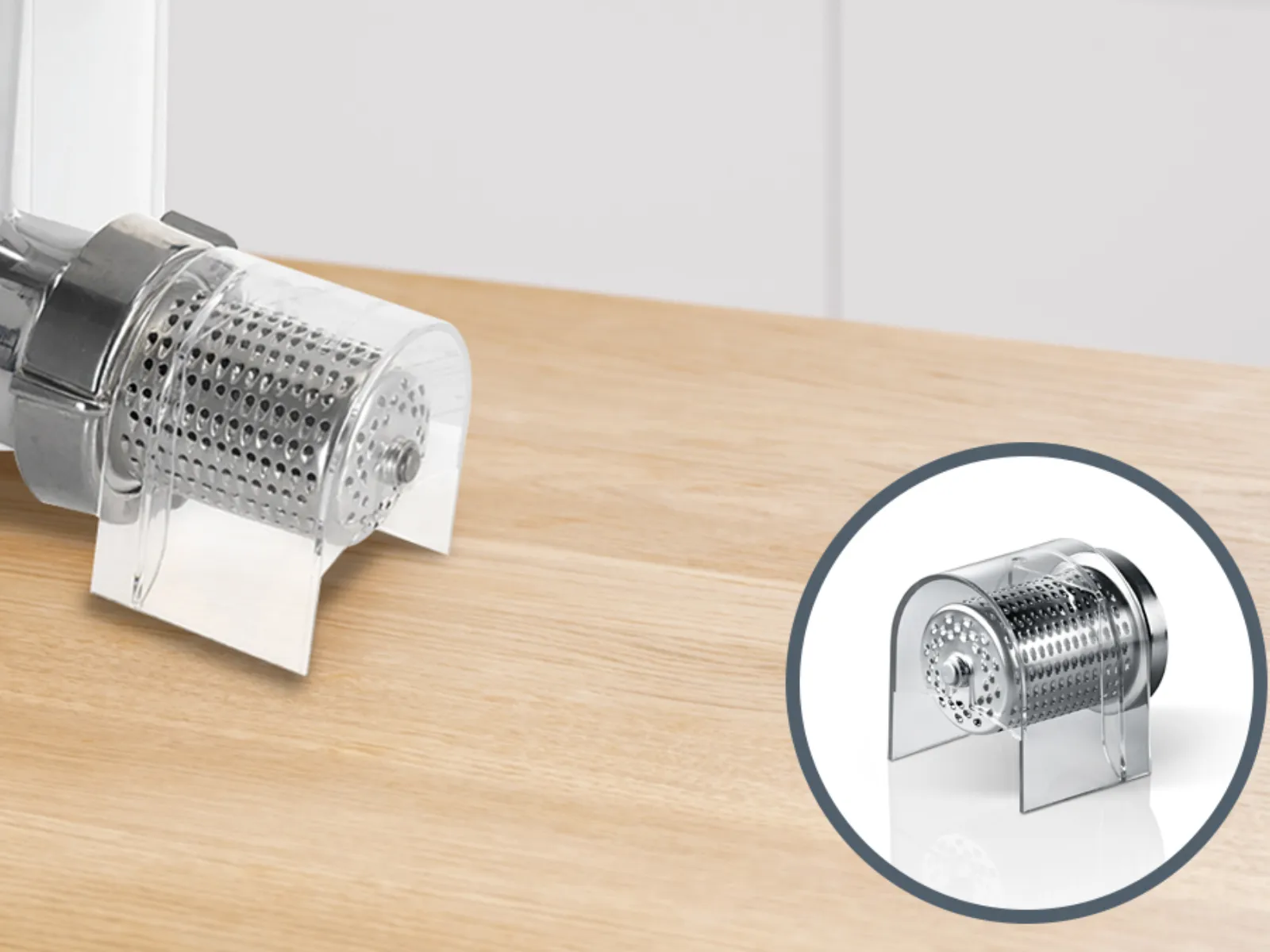 Meat grinder attachment for kitchen appliance, chrome metal finish, on wooden surface.
