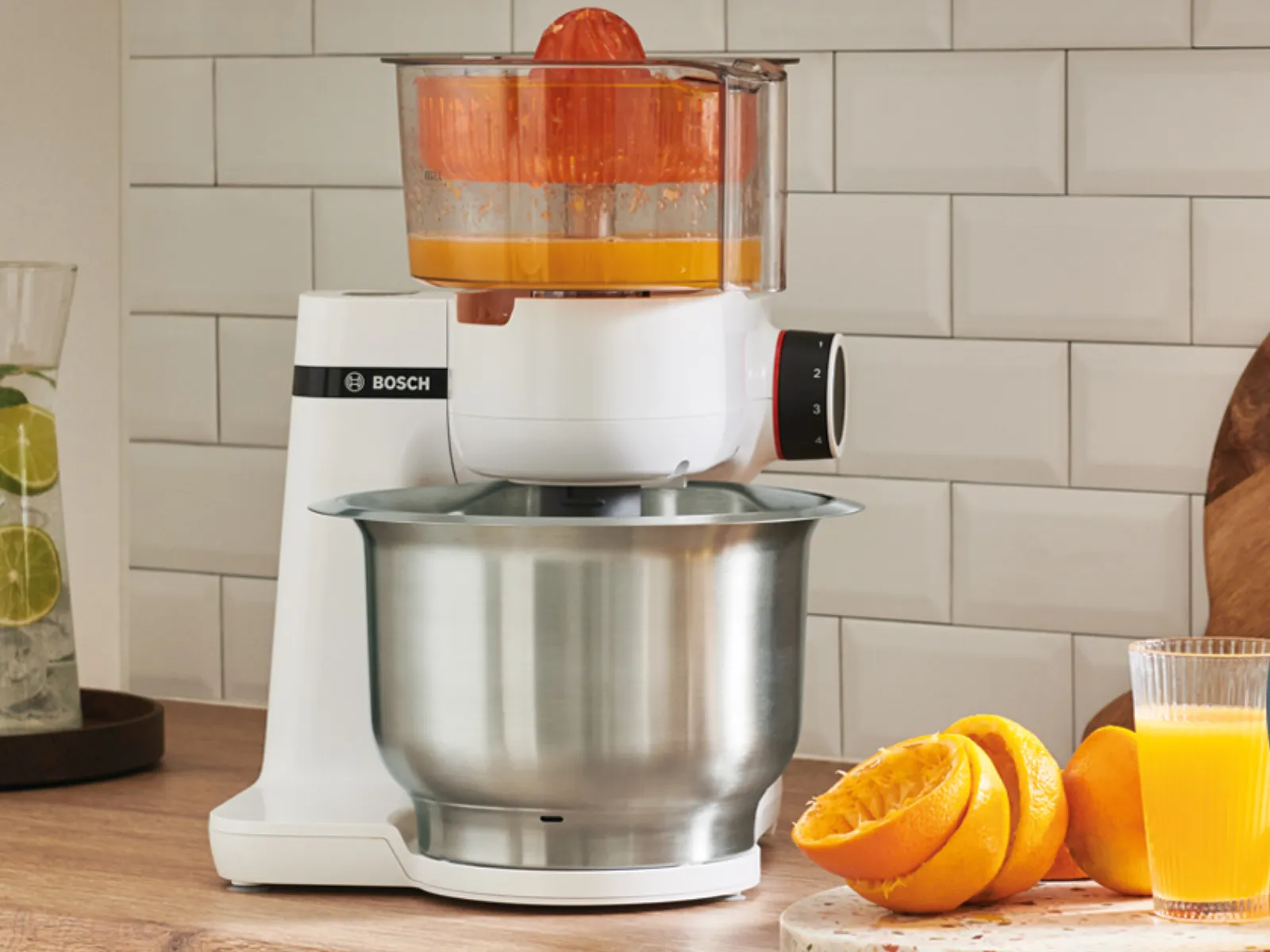Kitchen appliance, citrus juicer, oranges, wooden board, kitchen tiles, cooking utensils.