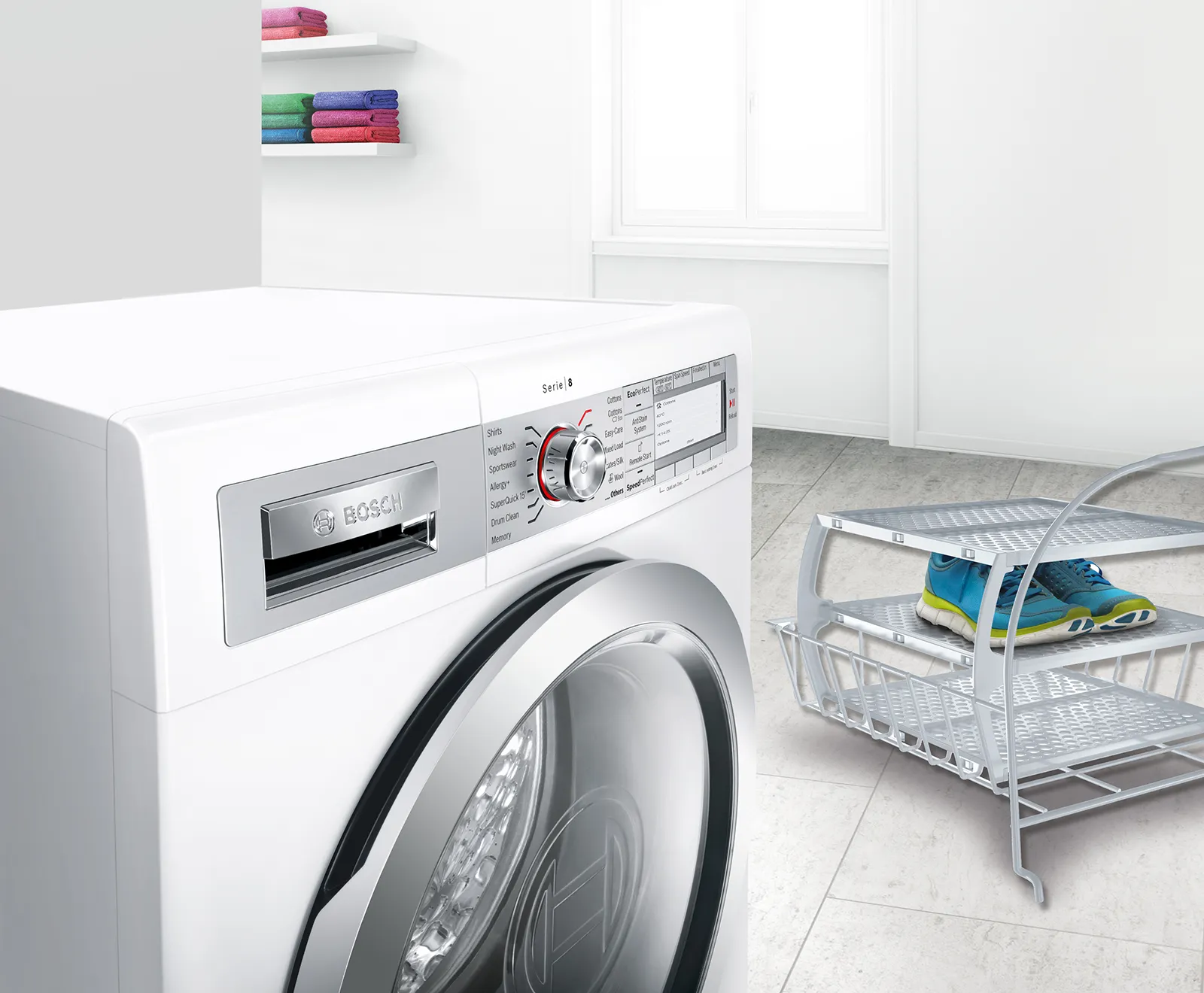 Bosch-tvättmaskin i en ljus tvättstuga med ett par träningsskor på en ställning bredvid.