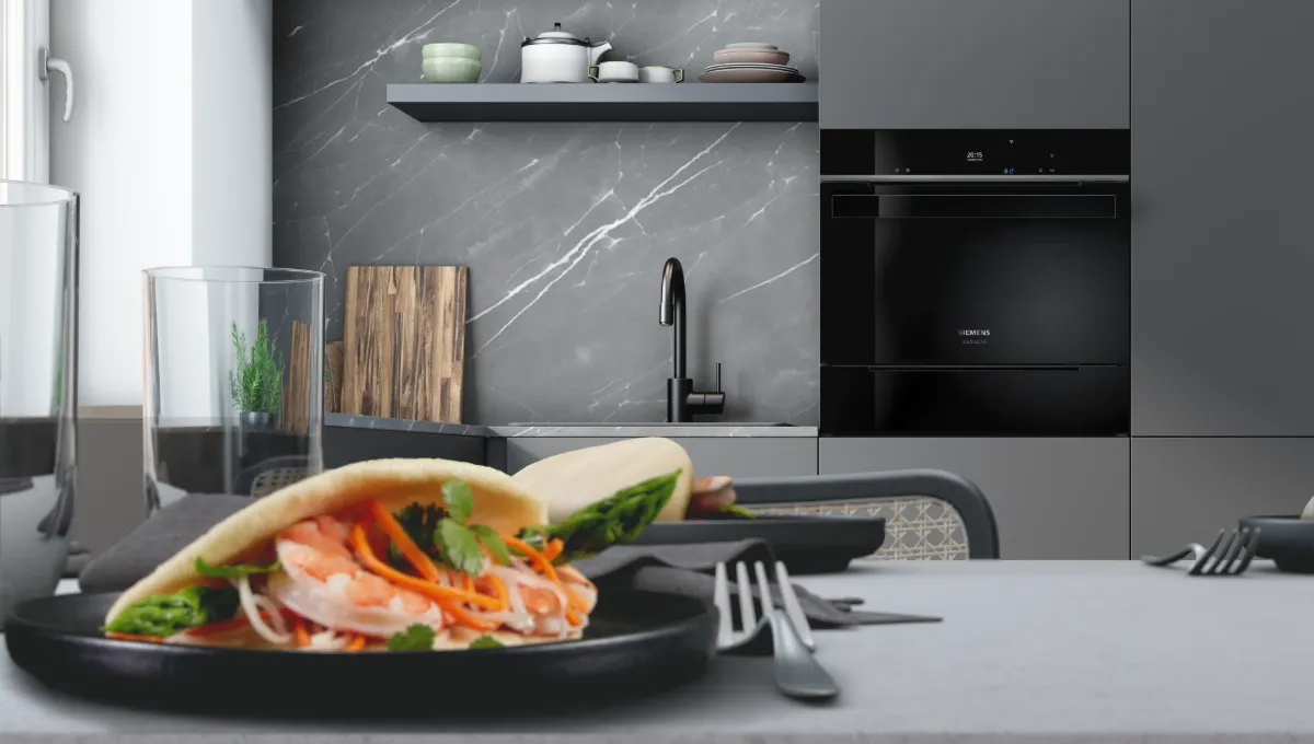 Cuisine moderne avec des placards gris, une crédence en marbre, des étagères ouvertes, et un sandwich sur une assiette posé sur un plan de travail gris, accompagné de couverts.