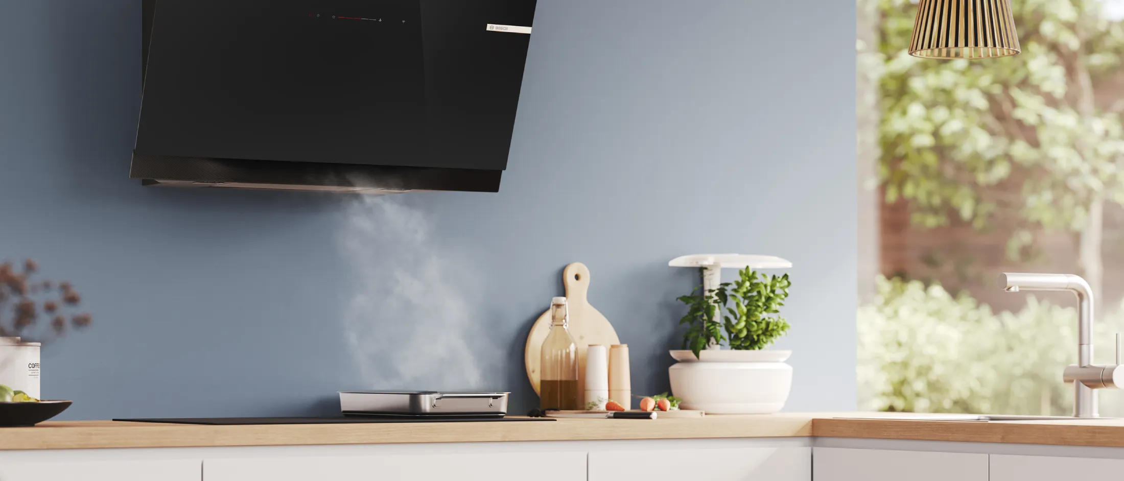 Minimalist kitchen countertop with a mounted TV, cutting board, olive oil bottle, salt and pepper shakers, herbs, carrots, and tea and coffee canisters.