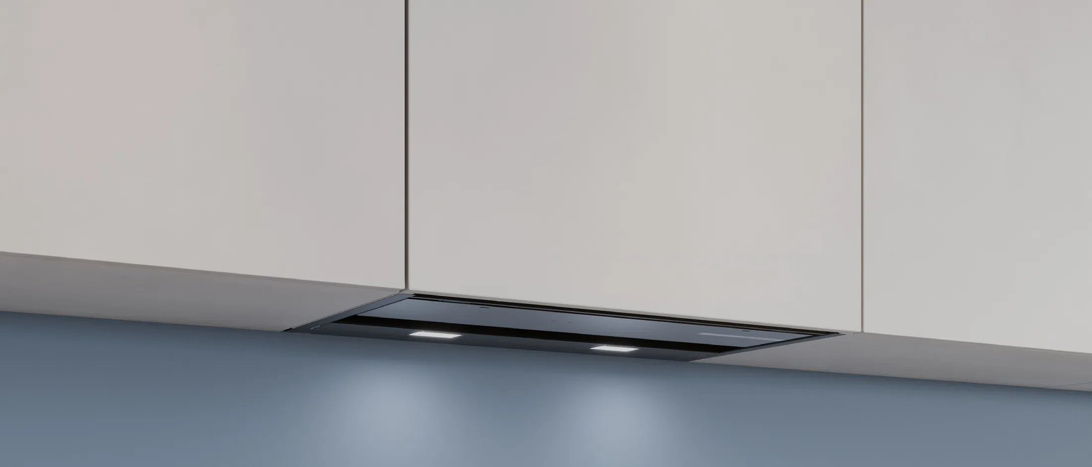 Under-cabinet range hood with built-in lights installed beneath white kitchen cabinets against a blue wall.