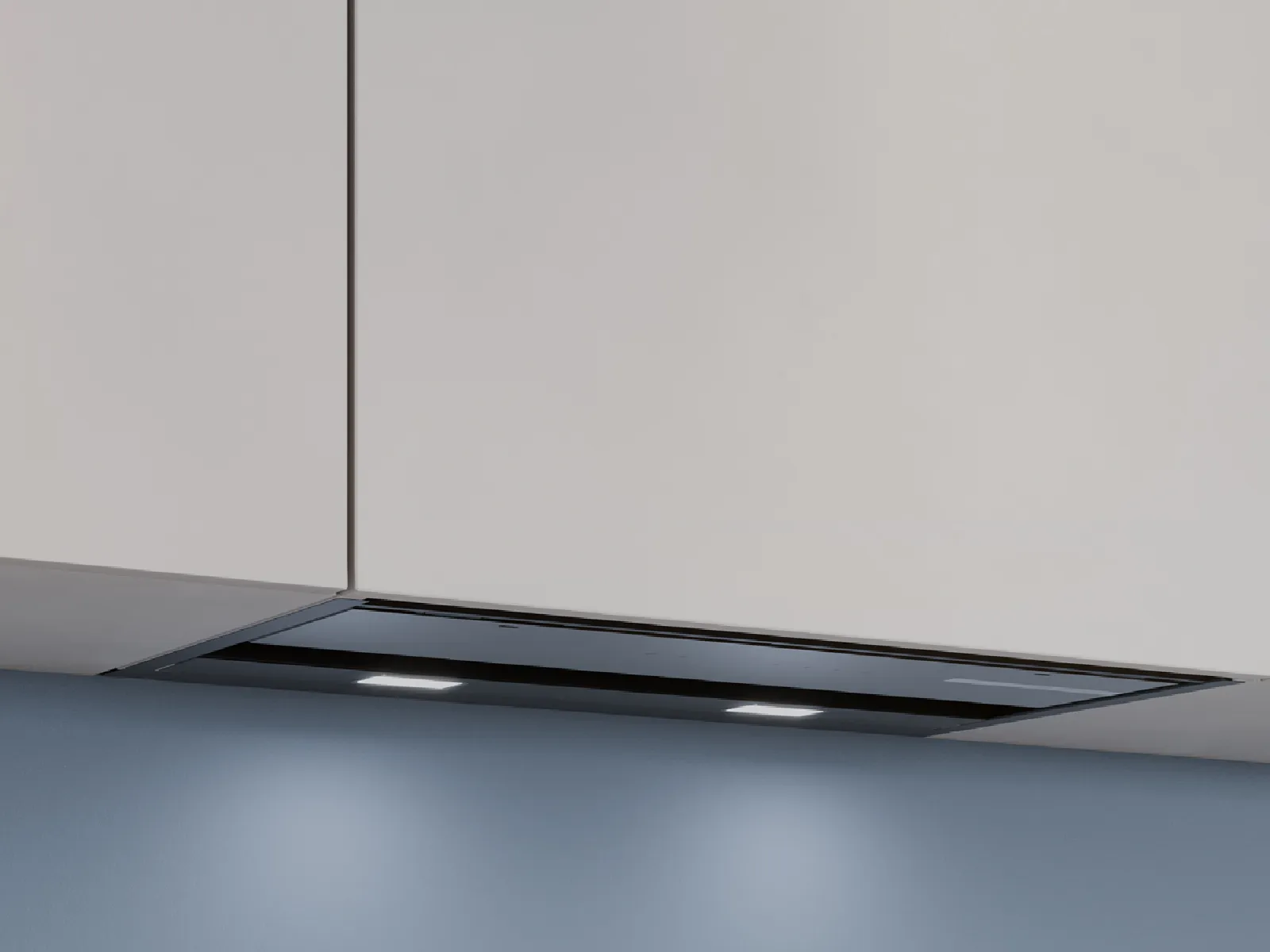 Sleek modern built-in black kitchen range hood with integrated lights under white cabinetry and a soft blue wall background.