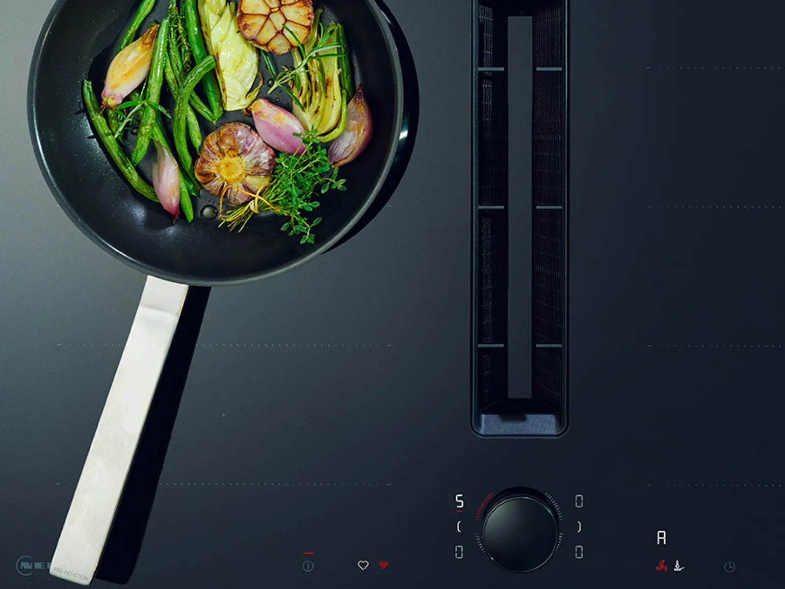Cooking pan with fresh vegetables, herbs, and spices on a dark kitchen counter.