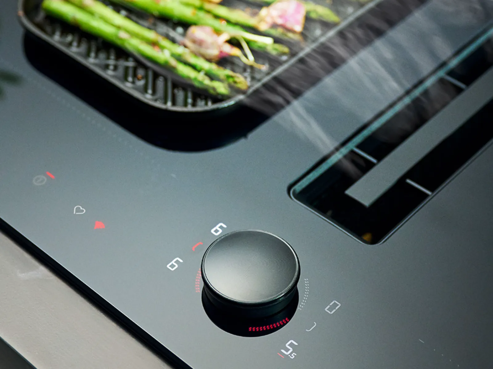 Vented cooktop close-up in Deep Black with green vegetables in griddle pan