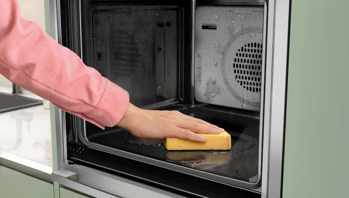 Gelöste Rückstände werden nach Intensive Steam Clean mit einem Schwamm aus dem NEFF Backofen ausgewischt.