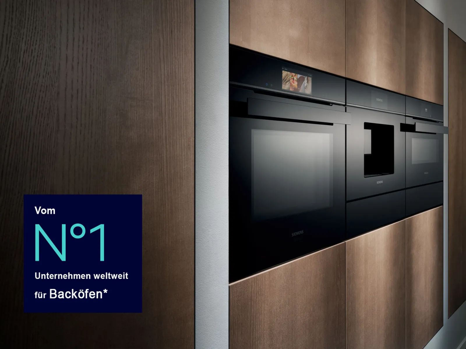 Integrierte schwarze Siemens-Einbaugeräte (Backofen, Kaffeemaschine, Kompaktgerät) in einer modernen Küche mit dunklen Holzschränken, ergänzt durch ein blaues Textfeld "Vom N°1 Unternehmen weltweit für Backöfen*" links unten.