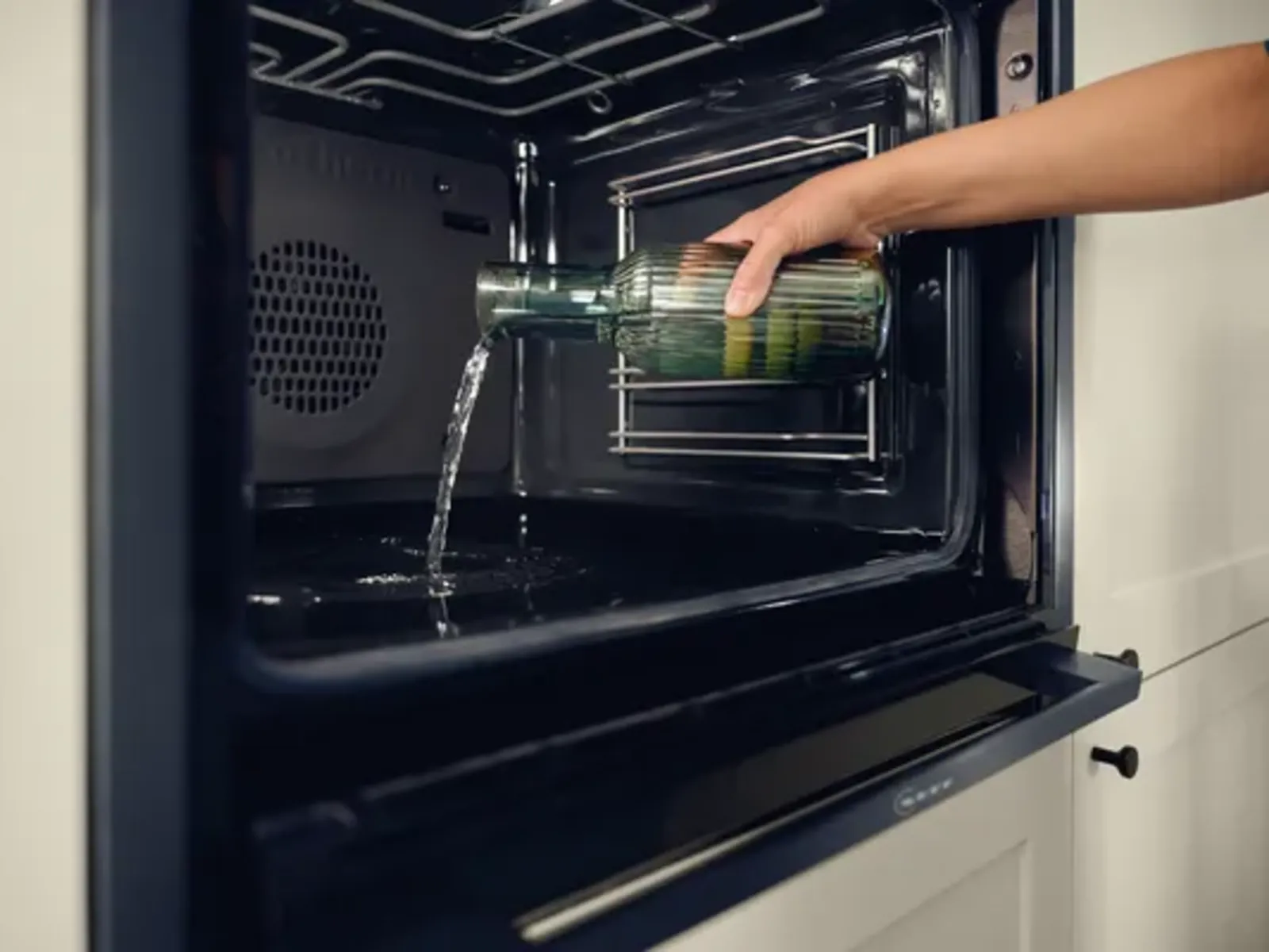 Wasser wird für die Easy Clean Reinigungshilfe in den Garraum eines NEFF Backofens gegossen.