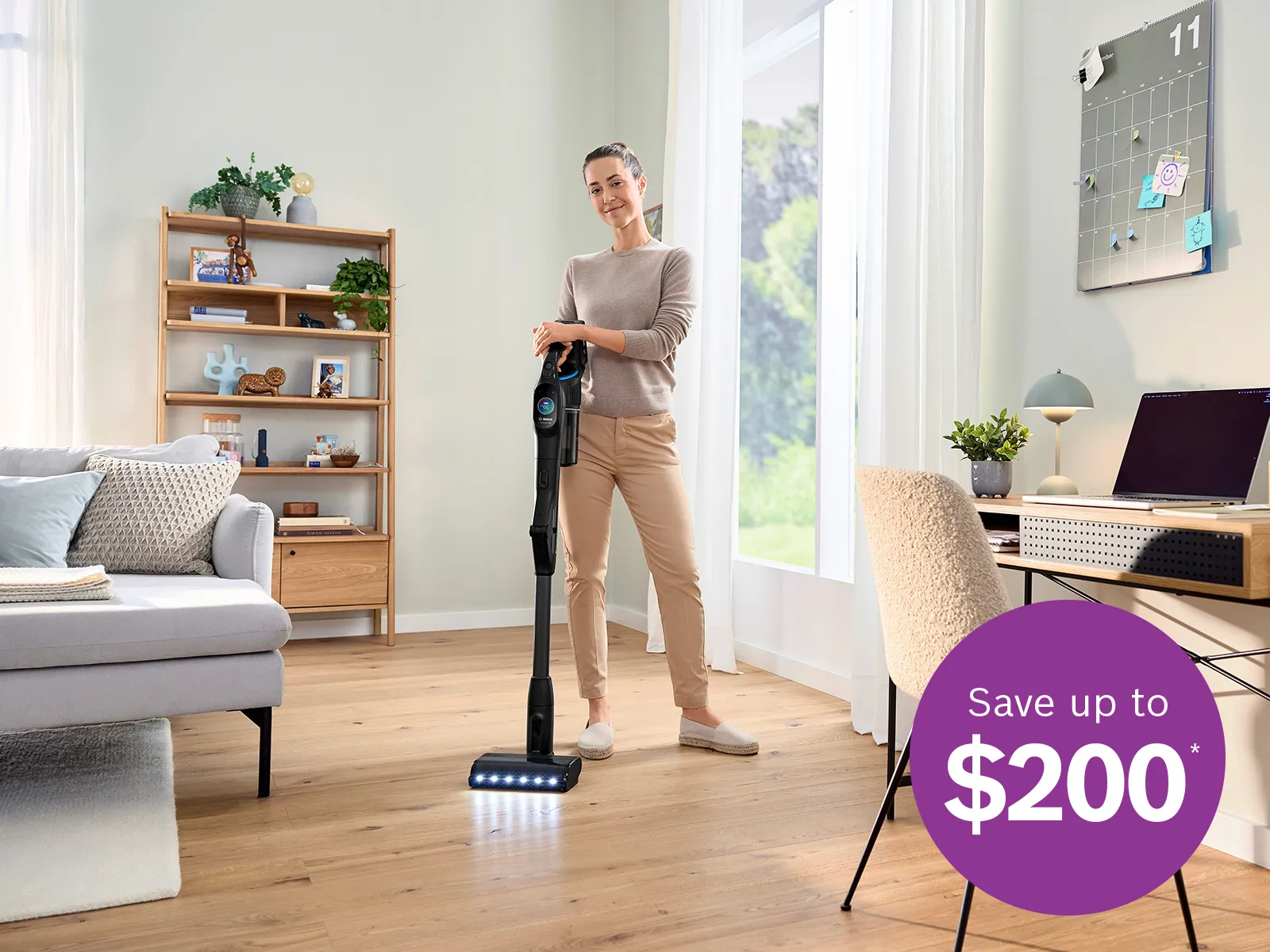 Person vacuuming a bright living room with a cordless vacuum; purple badge advertises savings up to $200.