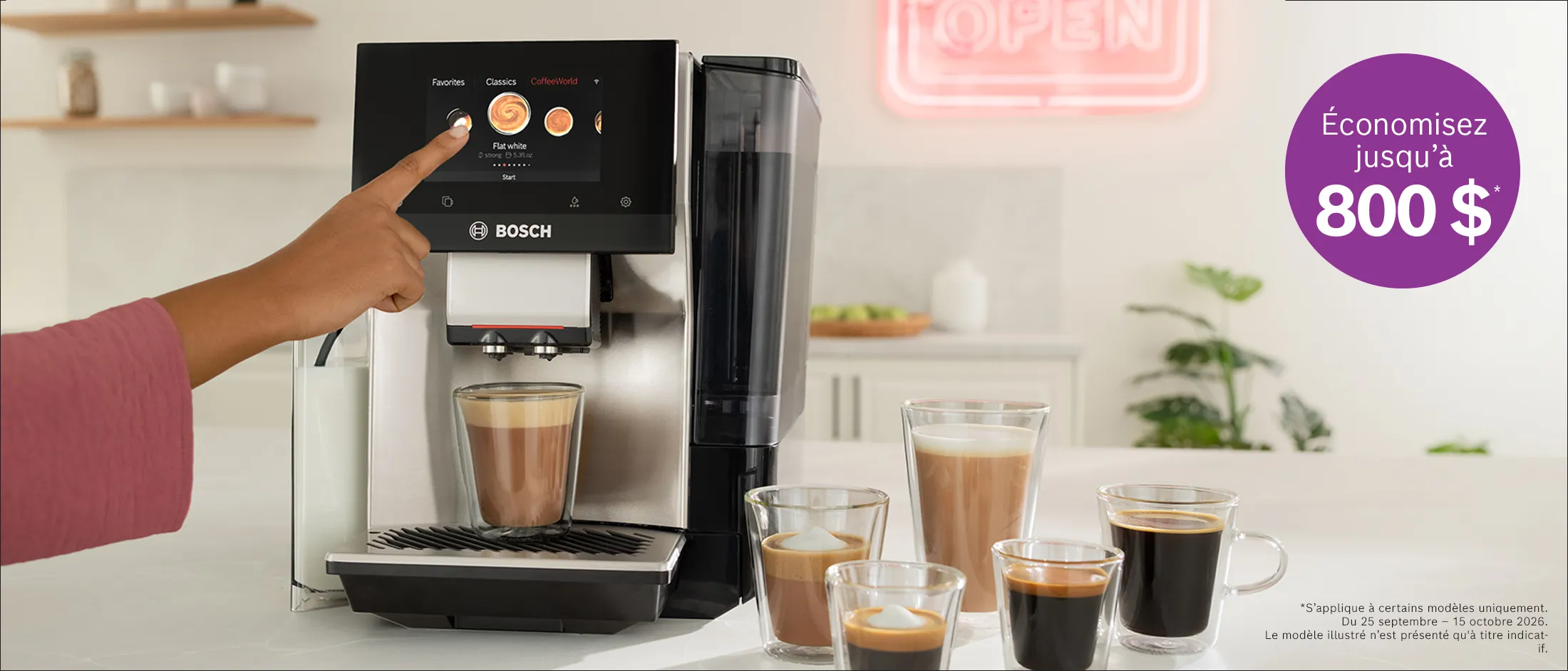 Personne sélectionnant une option de café sur une machine à espresso Bosch, avec des cafés fraîchement infusés dans des tasses en verre et une enseigne au néon "OPEN" (fr-CA)
