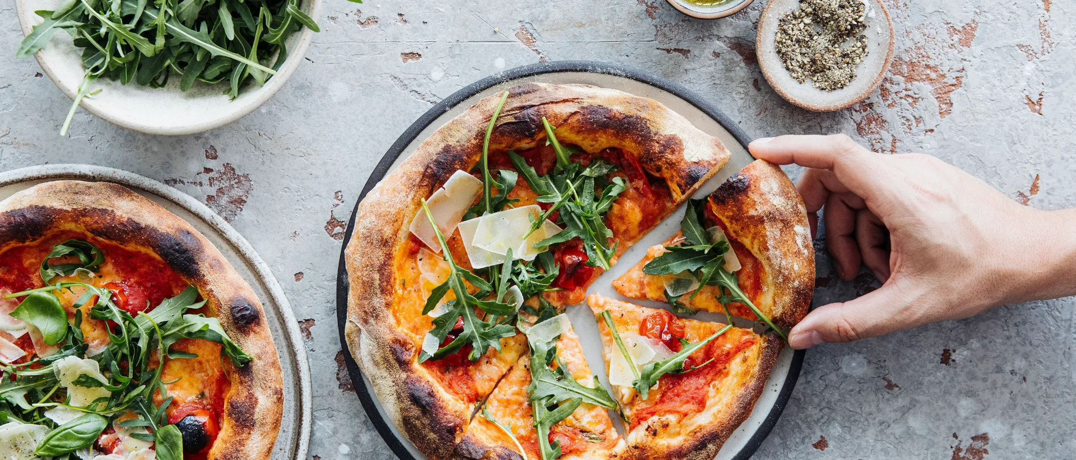 Zwei neapolitanische Pizzen mit Rucola und Parmesanspänen auf hellem Untergrund