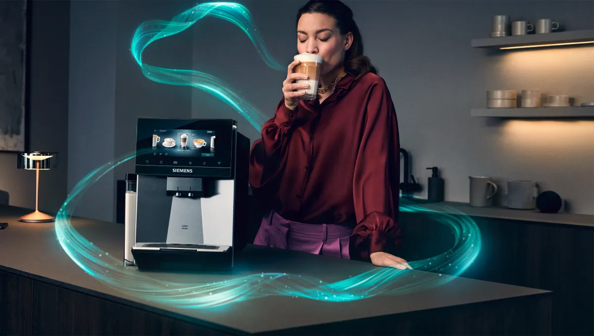 Kvinna som dricker kaffe bredvid en kaffemaskin, medan lysande turkosa ljusstrimmor virvlar runt en modern köksö.