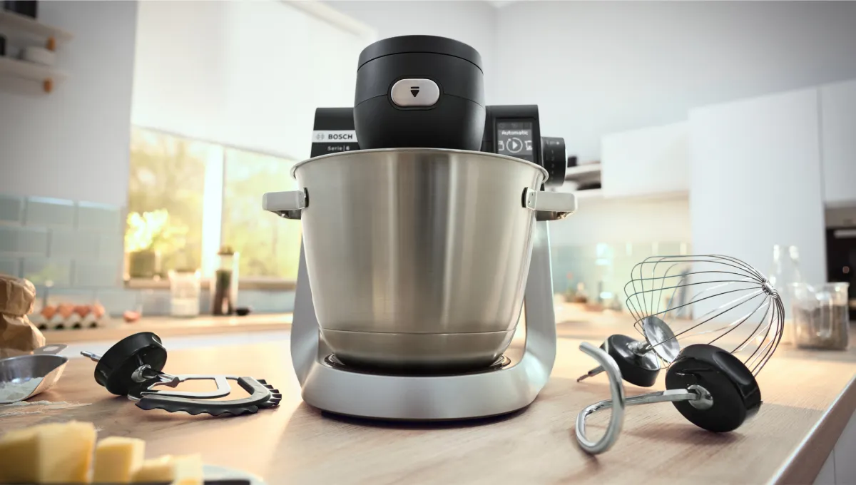 Apparecchi da cucina tra cui un mixer stand, frusta e altri utensili da cucina su un piano di lavoro.