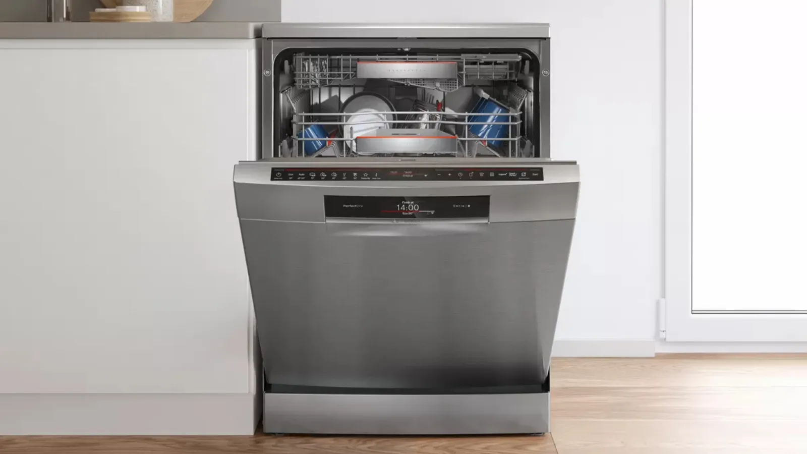 Open stainless steel dishwasher loaded with dishes in a modern kitchen.