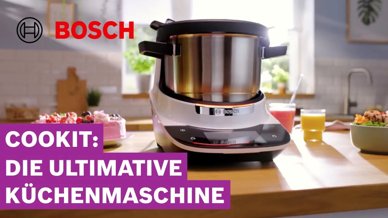 Robot de cuisine Bosch avec bol en acier inoxydable sur un plan de travail, à côté de plats et de boissons ; le texte en français se lit comme suit : « Cookit : le robot de cuisine ultime. »