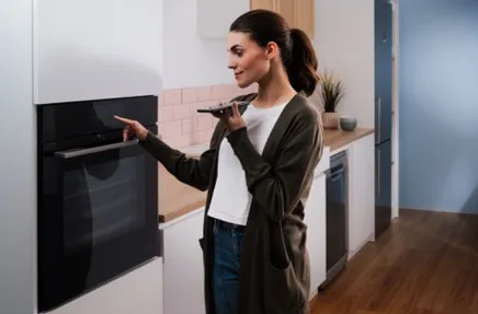alt-Smartphone avec application ouverte de diagnostic à distance tenu dans la main dans une cuisine.
