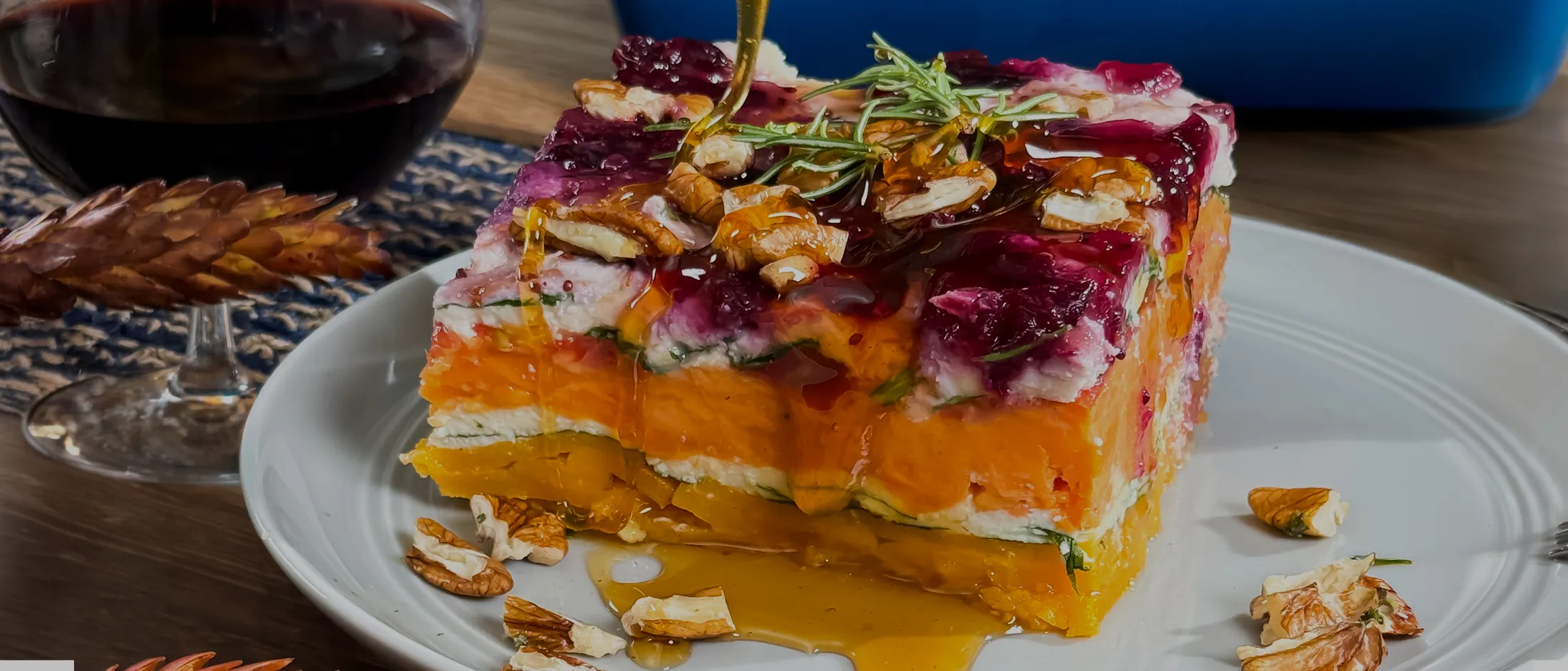 Butternut Squash Lasagna with a honey dipper drizzling honey on top and a glass of wine in the back