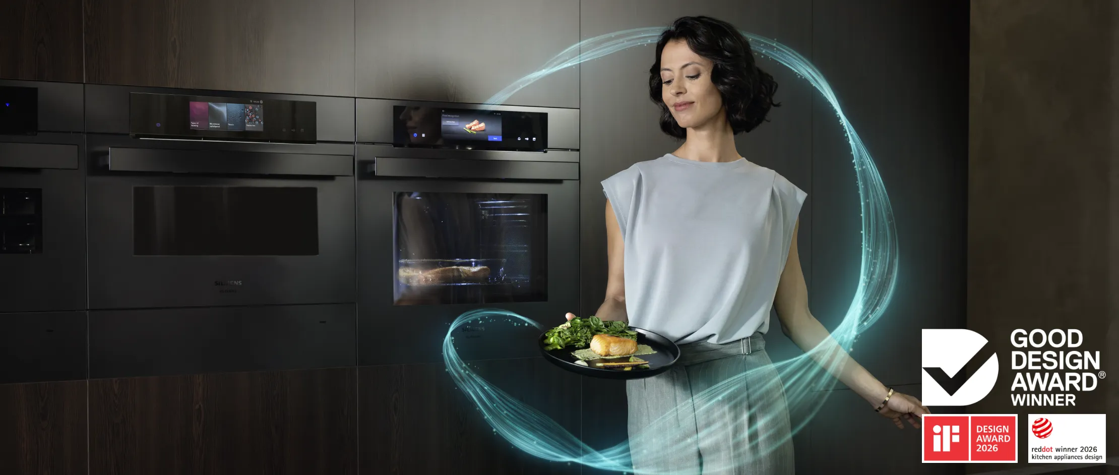 Person holding a plate of cooked salmon and vegetables in a modern kitchen with integrated smart ovens.