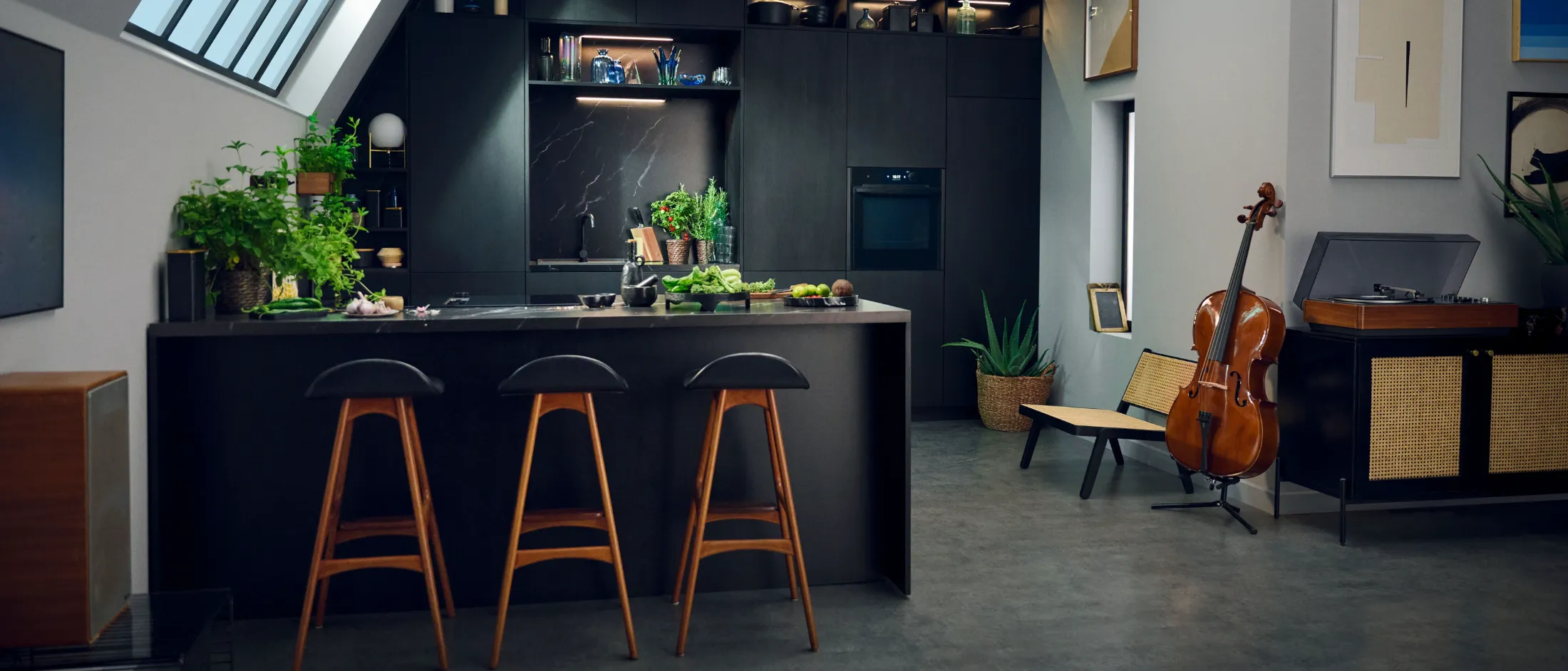 Cucina moderna con mobili neri, sgabelli da bar e un violoncello nella zona giorno.