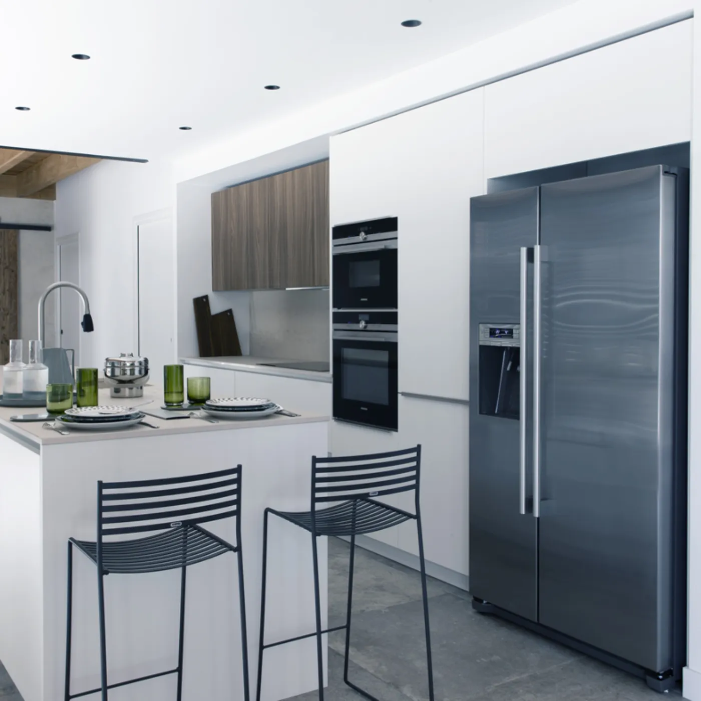 Cucina moderna con armadi bianchi, elettrodomestici in acciaio inossidabile e travi in legno.