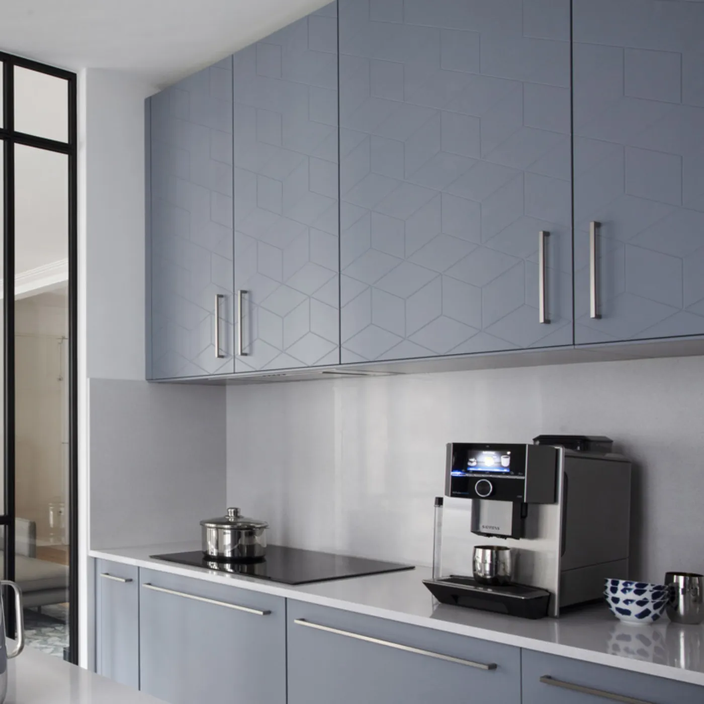 Cucina moderna con armadi grigi, elettrodomestici in acciaio inossidabile e parete divisoria in vetro.