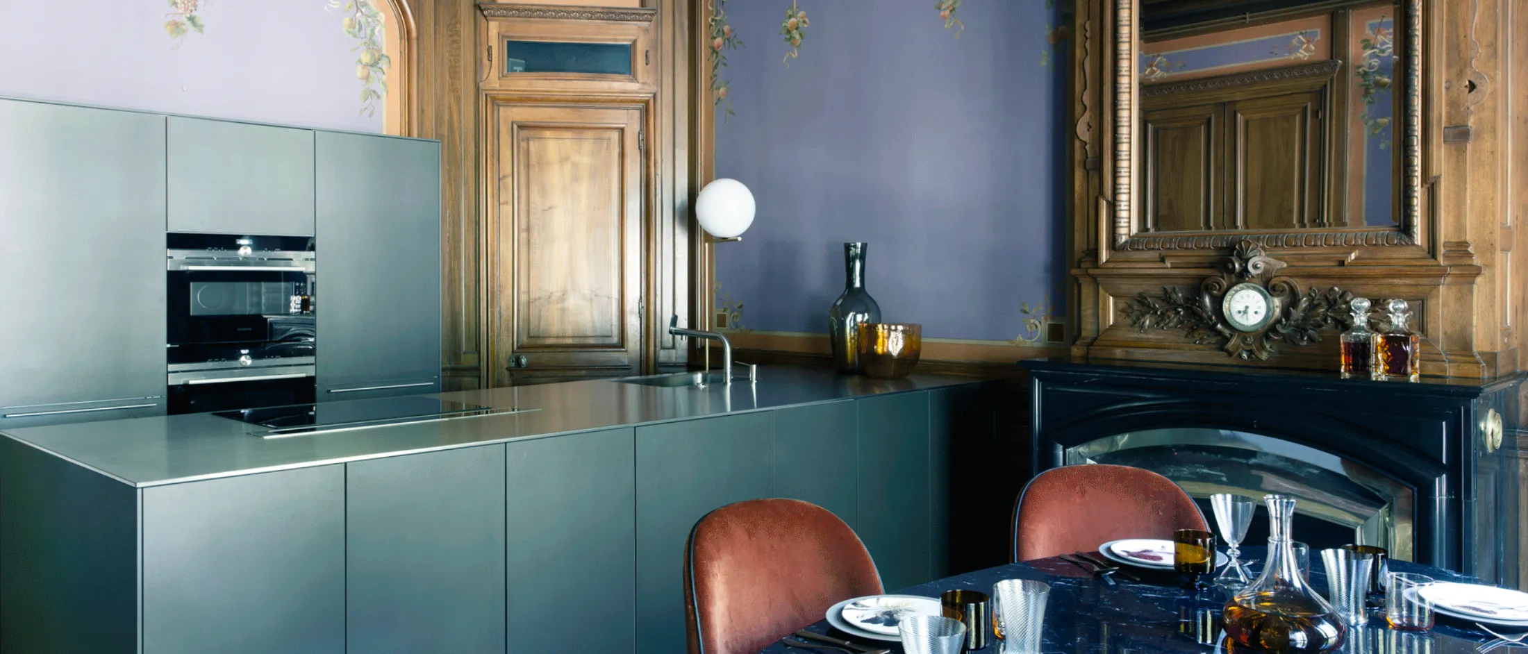 Elegante cucina con moderni armadi verdi, mobili antichi e dettagli architettonici decorati.