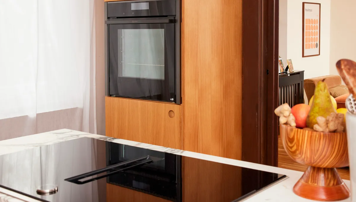 Modern kitchen with induction cooktop, oven, and wooden cabinets.