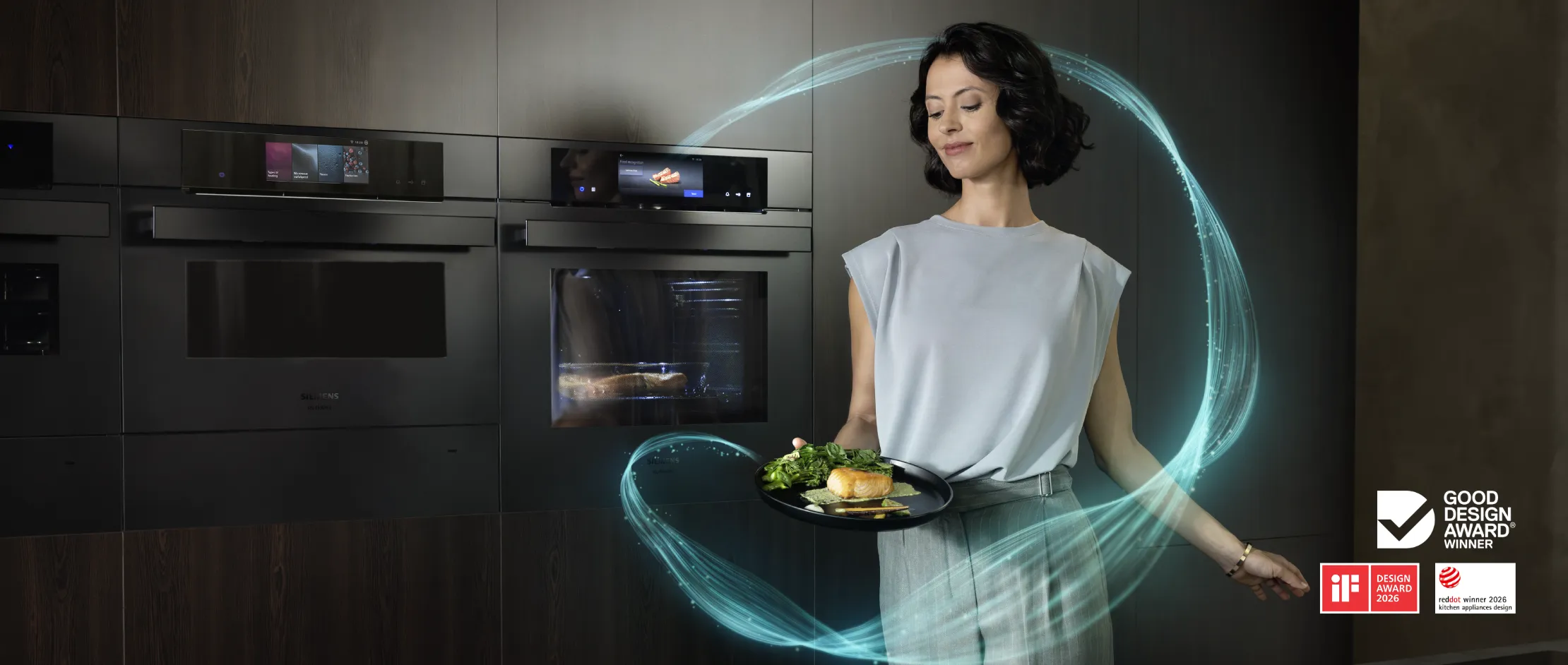 Person holding a plate of cooked salmon and vegetables in a modern kitchen with integrated smart ovens.