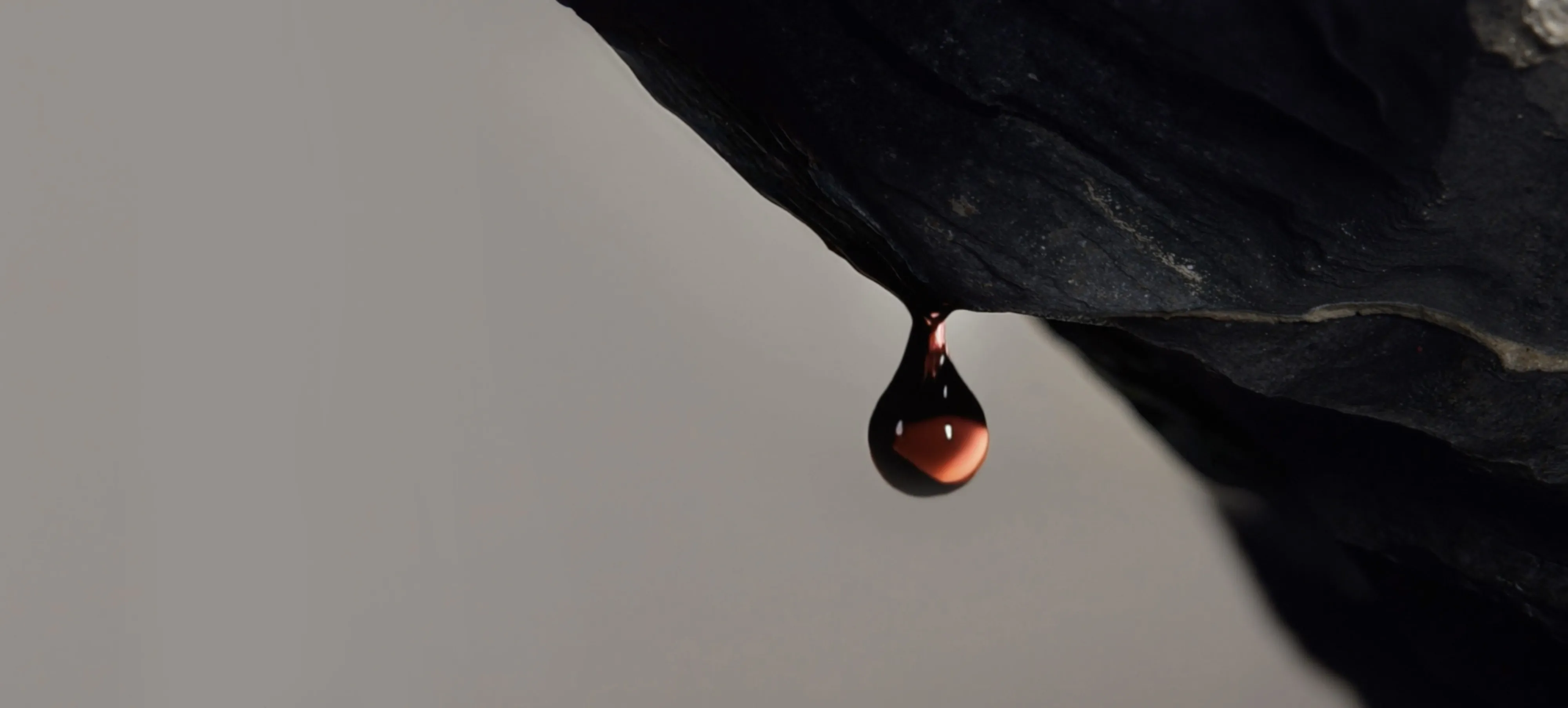 A droplet of wine falls from an overhanging rock