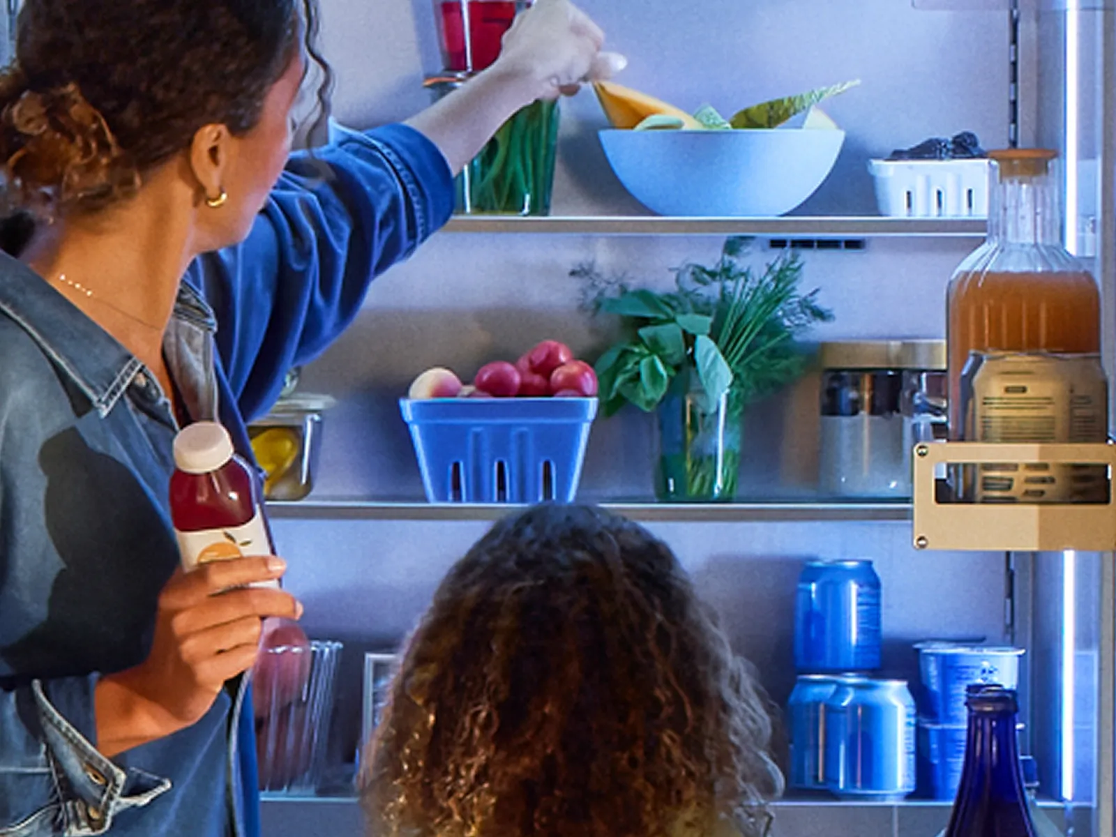 open Thermador refrigerator column with mother and daughter placing groceries in