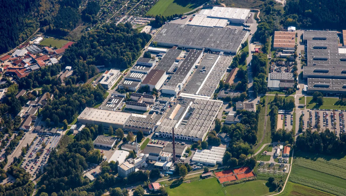 Luftaufnahme des BSH Werks in Traunreut mit Lagern, Parkplätzen und grünen Feldern nahe einer Kleinstadt.