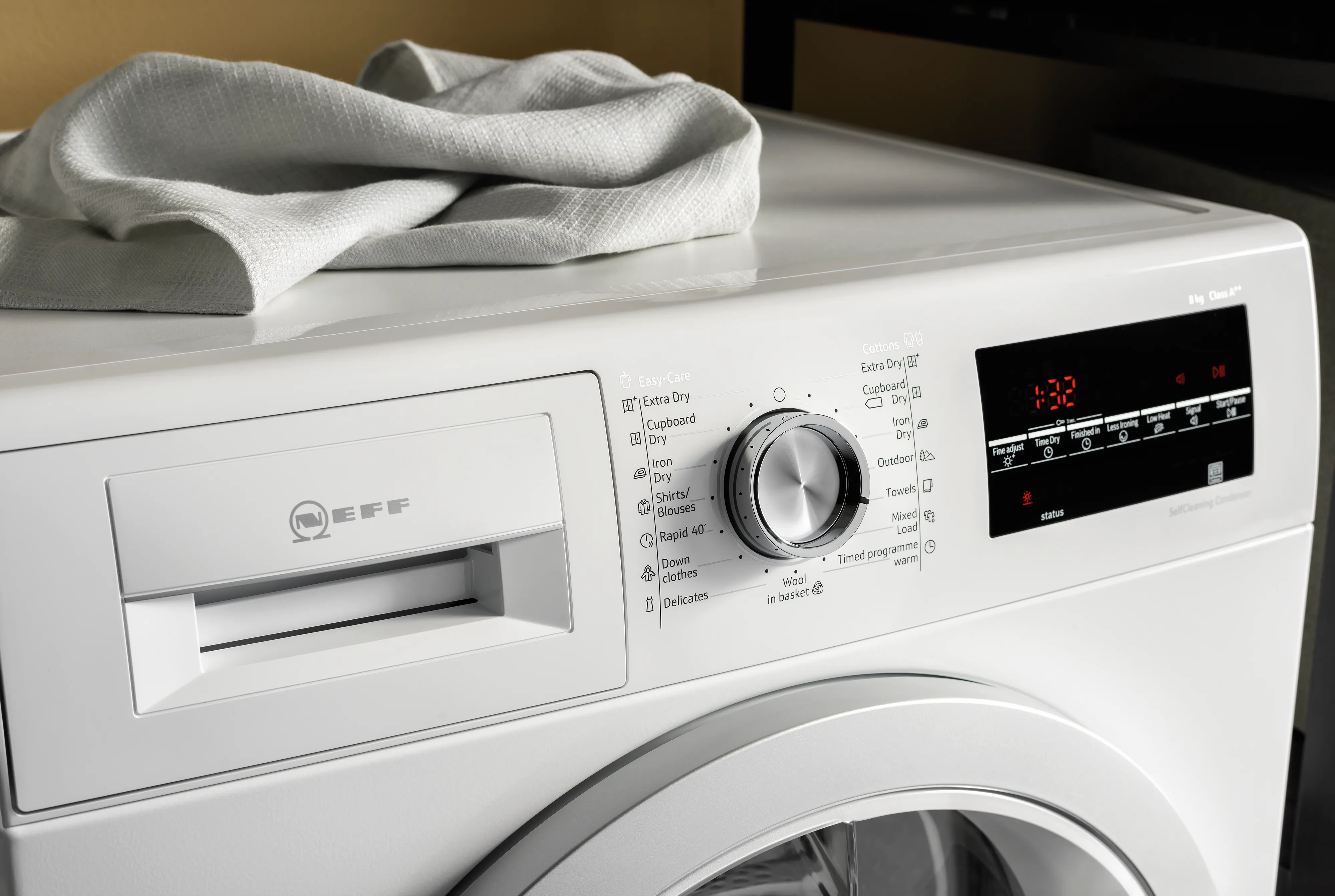 Beyaz çamaşır makinesi kontrol paneli ve açık kapı ile, towel on top.