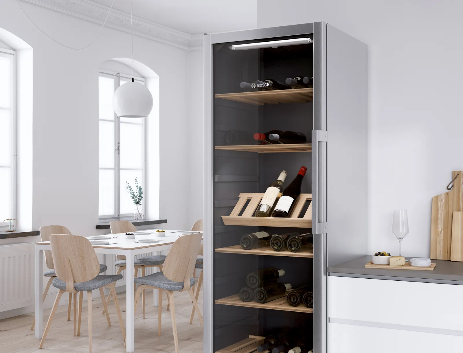 Un refroidisseur à vin autonome Bosch rempli de diverses bouteilles de vin, situé dans une salle à manger moderne avec une table et des chaises, et une grande fenêtre en arrière-plan.