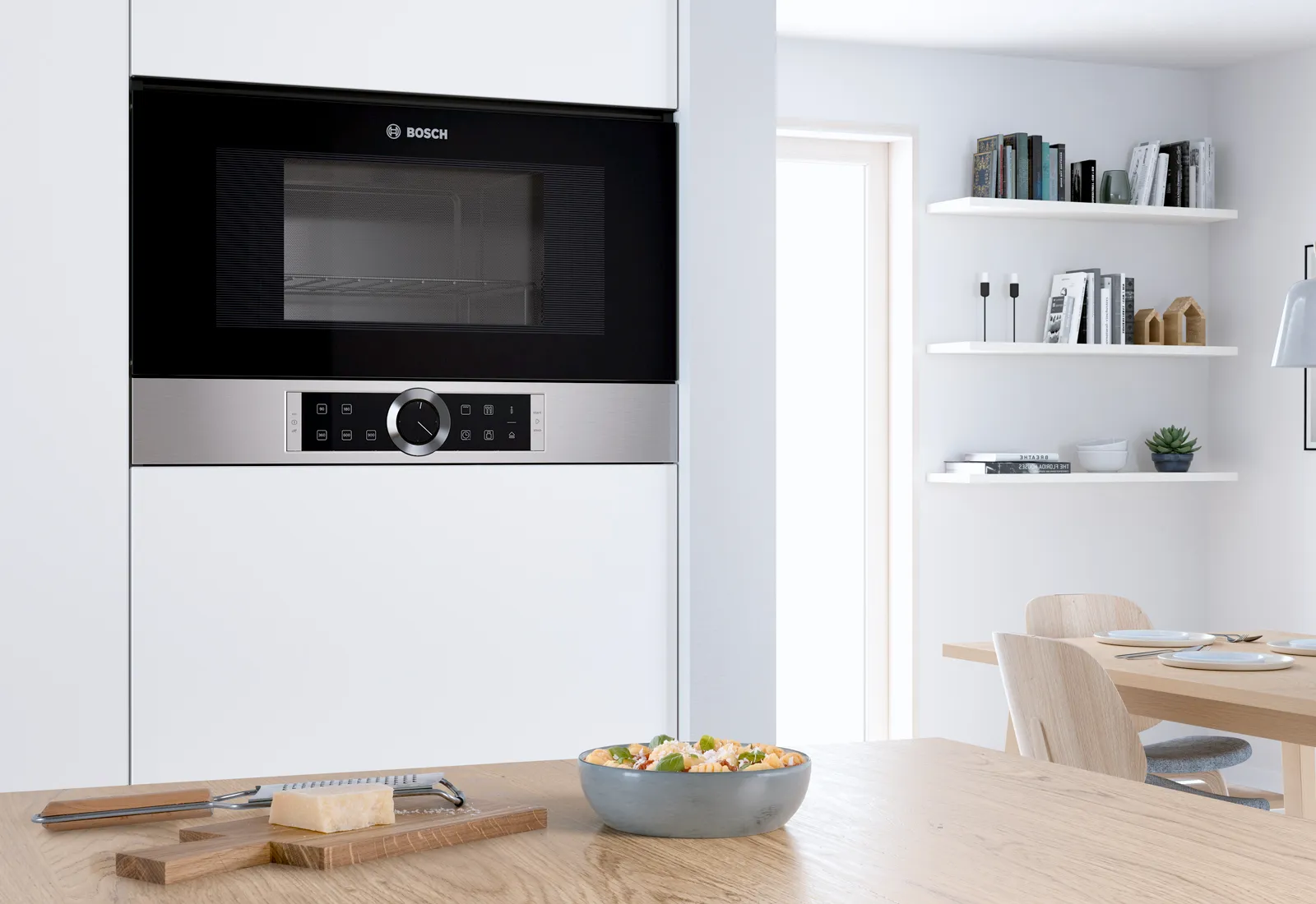 Modern kitchen with built-in Bosch microwave, wooden table with salad bowl and minimalist decor. 