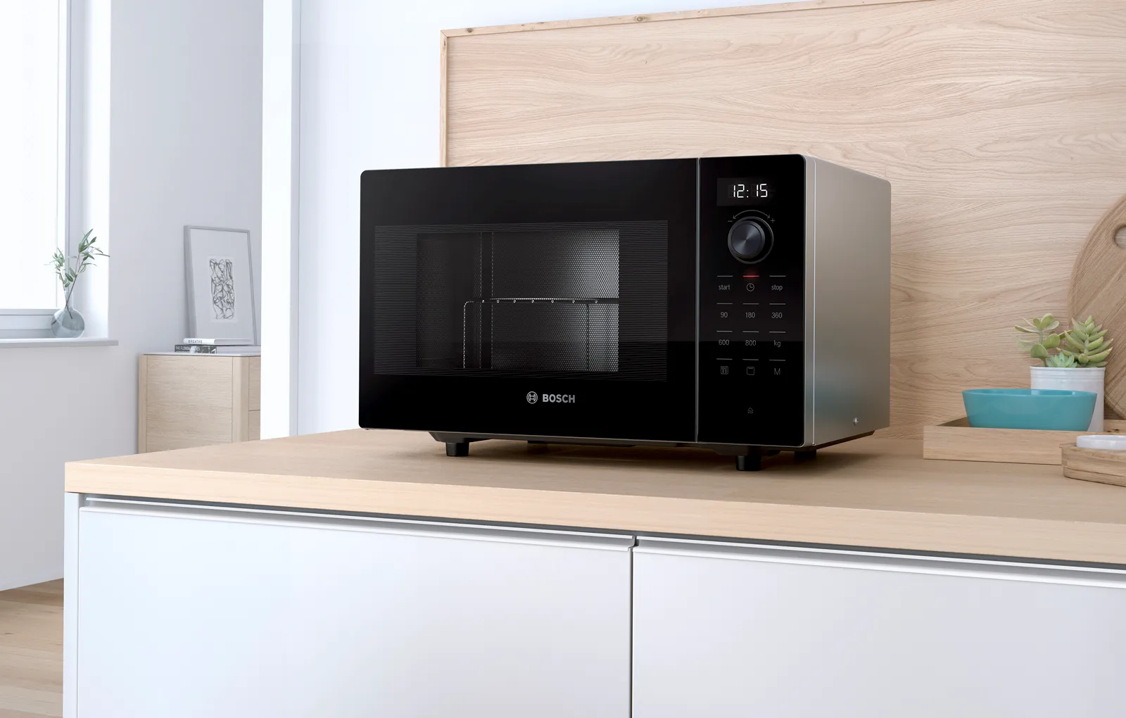 Black Bosch microwave on wood countertop showing 12:15 in modern minimalist kitchen.
