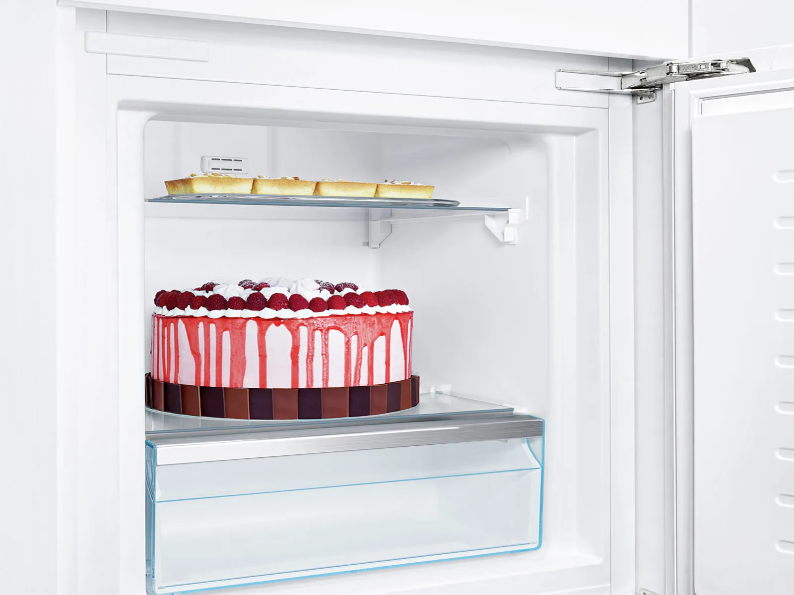Refrigerator interior with cake, fruit, and shelves.