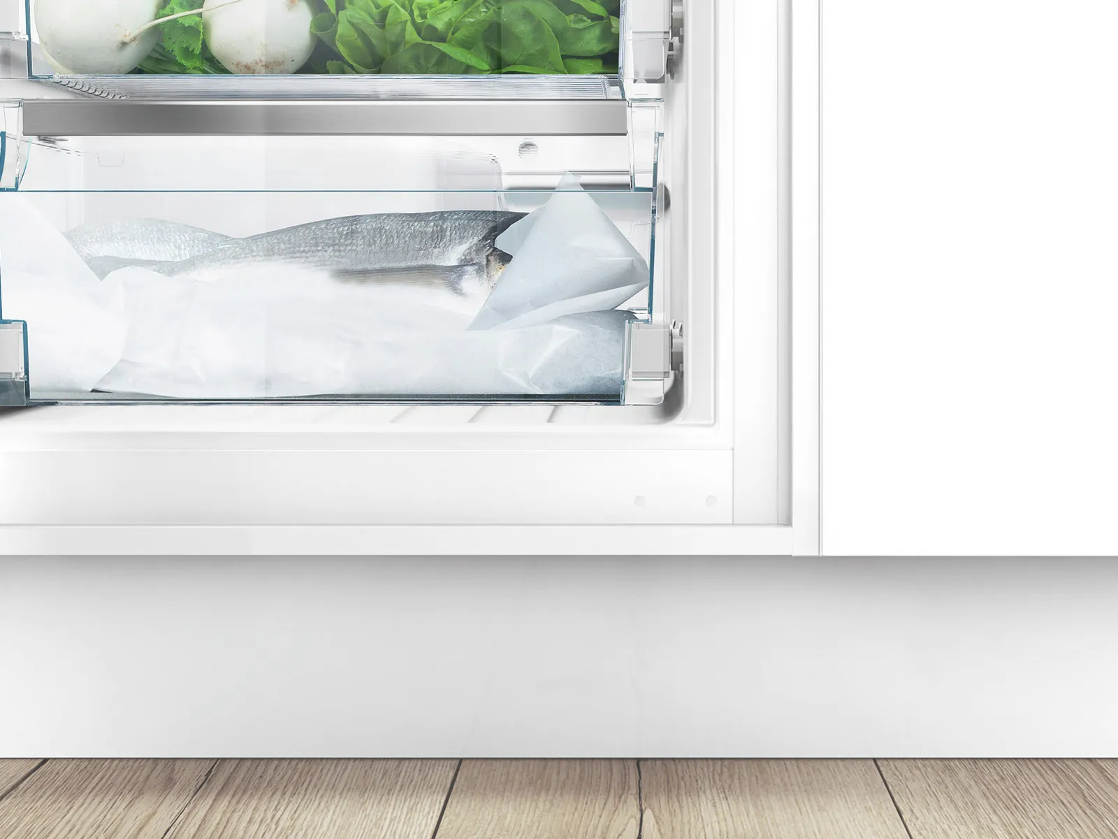 Open refrigerator with fish, vegetables, and empty space on wooden floor.