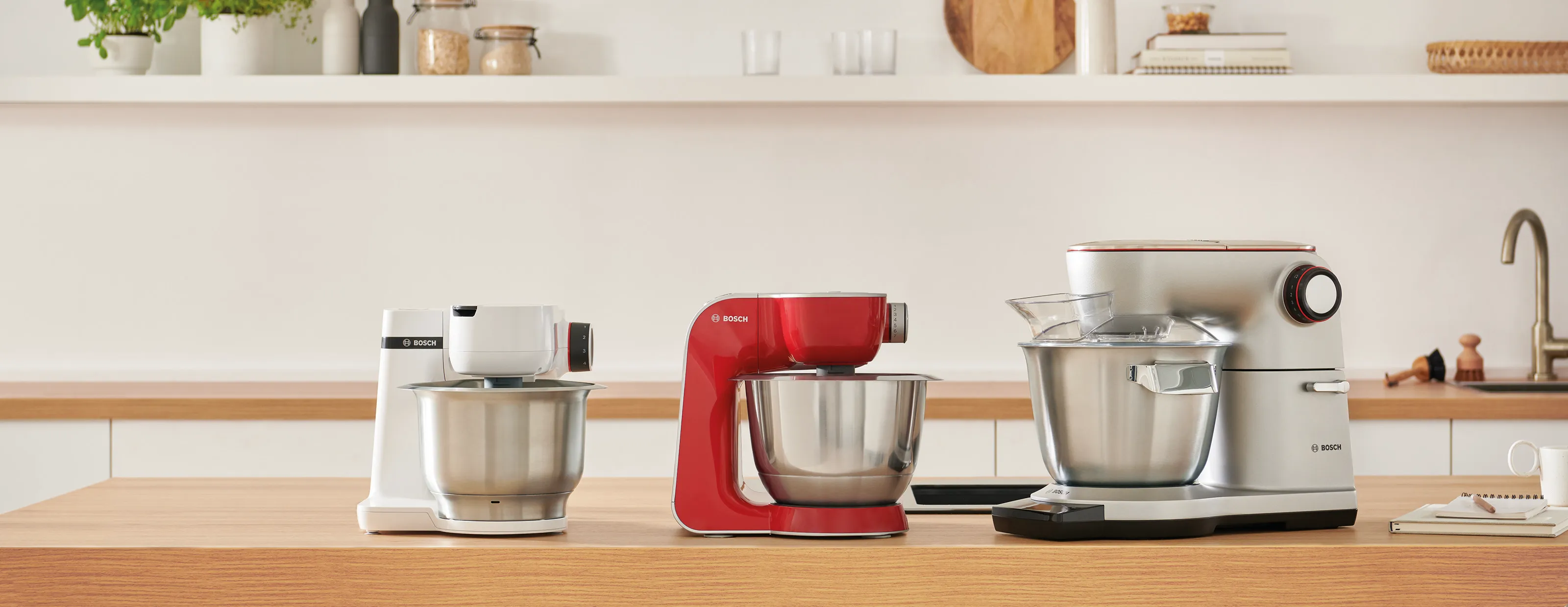 Bosch stand mixer and Bosch food processor on a wood worktop next to cake.