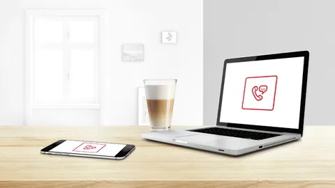 alt-Woman sitting in the kitchen holding a smartphone in her hand.