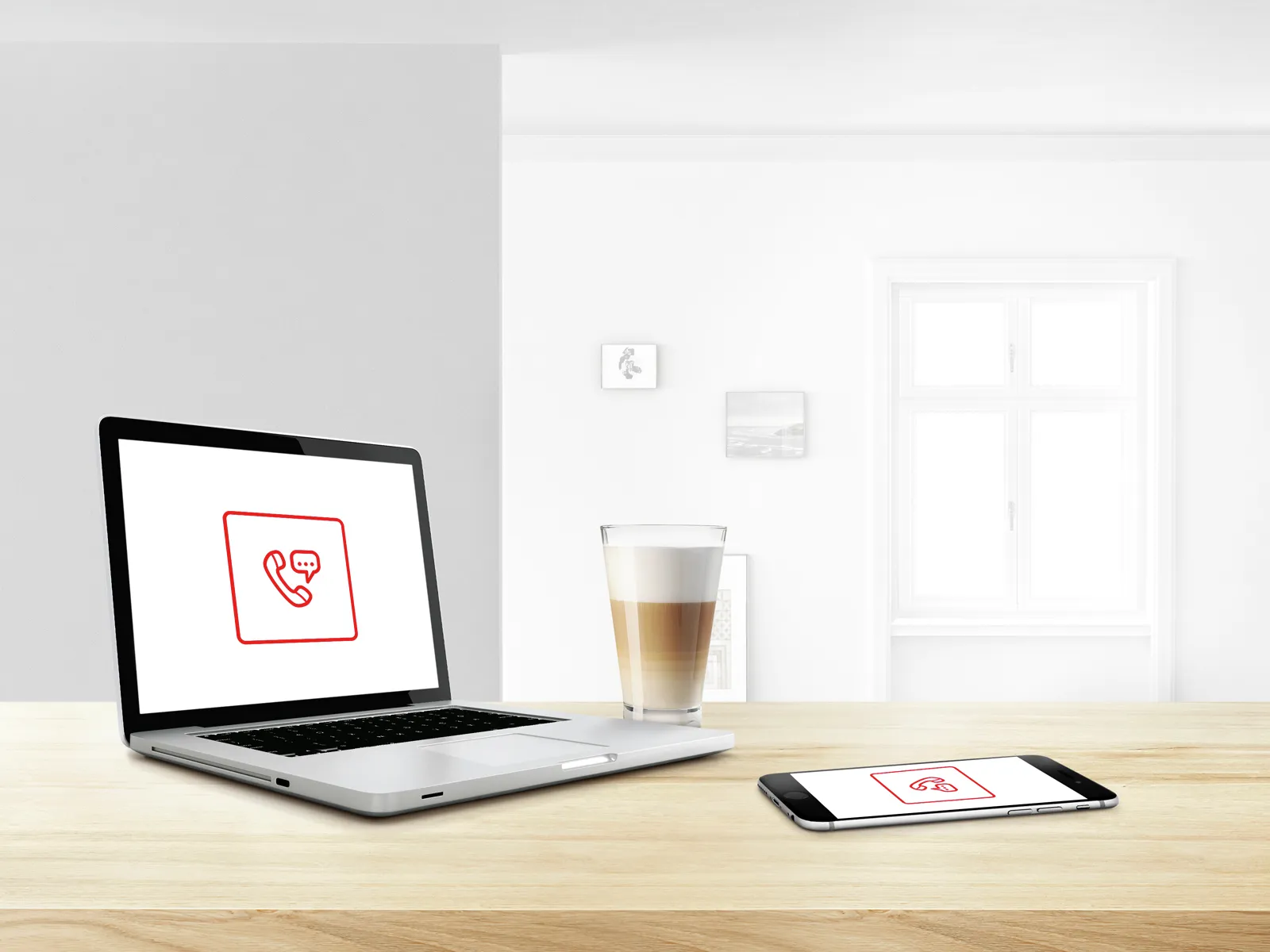 Laptop, smartphone, and coffee cup on a wooden desk in a minimalist office setting.