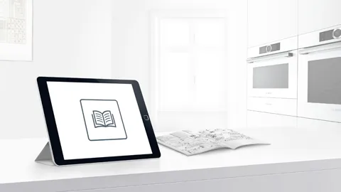 Tablet displaying book icon on kitchen counter, surrounded by Bosch kitchen appliances.
