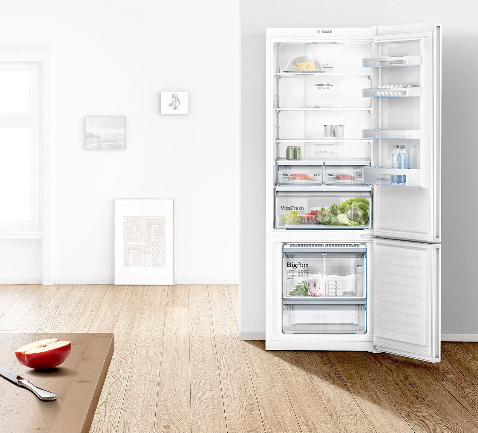 Interno cucina minimalista con frigorifero aperto, pavimento in legno e pareti bianche.