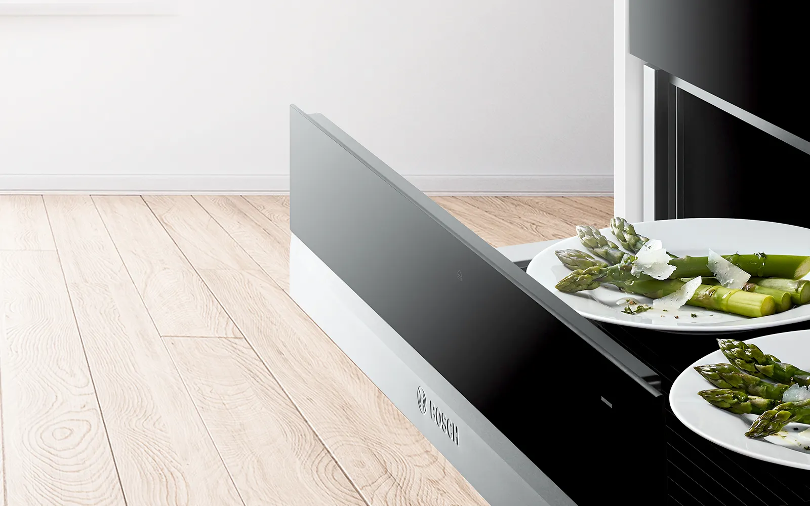 Moderne Küche mit schwarzem Gerät, frisches Gemüse auf Platten und Holzboden.