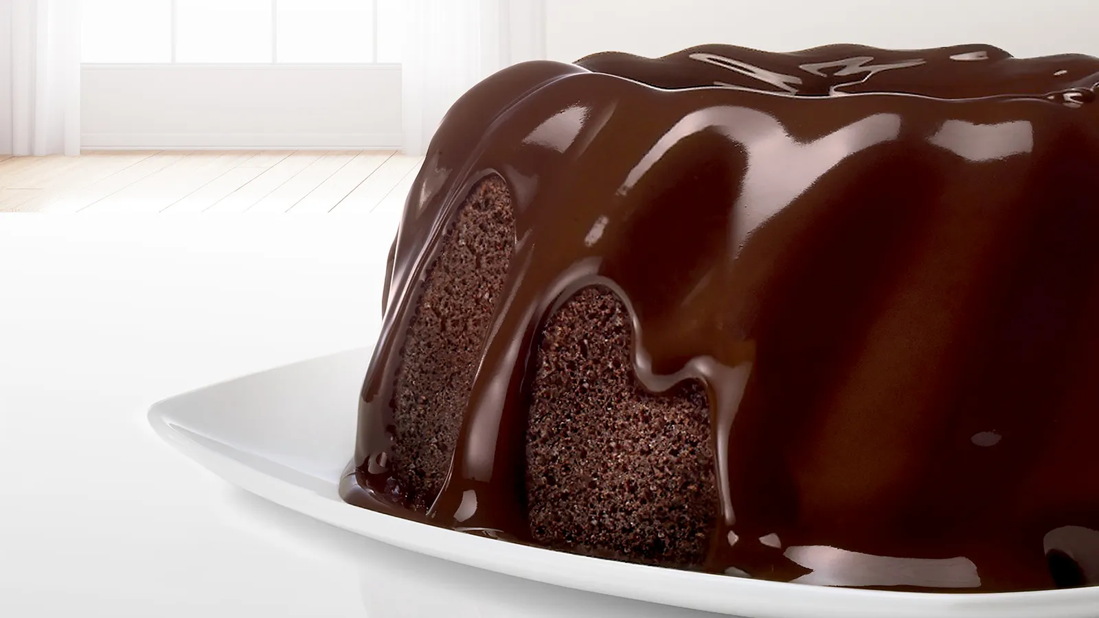 Chocolate cake with glossy dark chocolate glaze on a white plate.