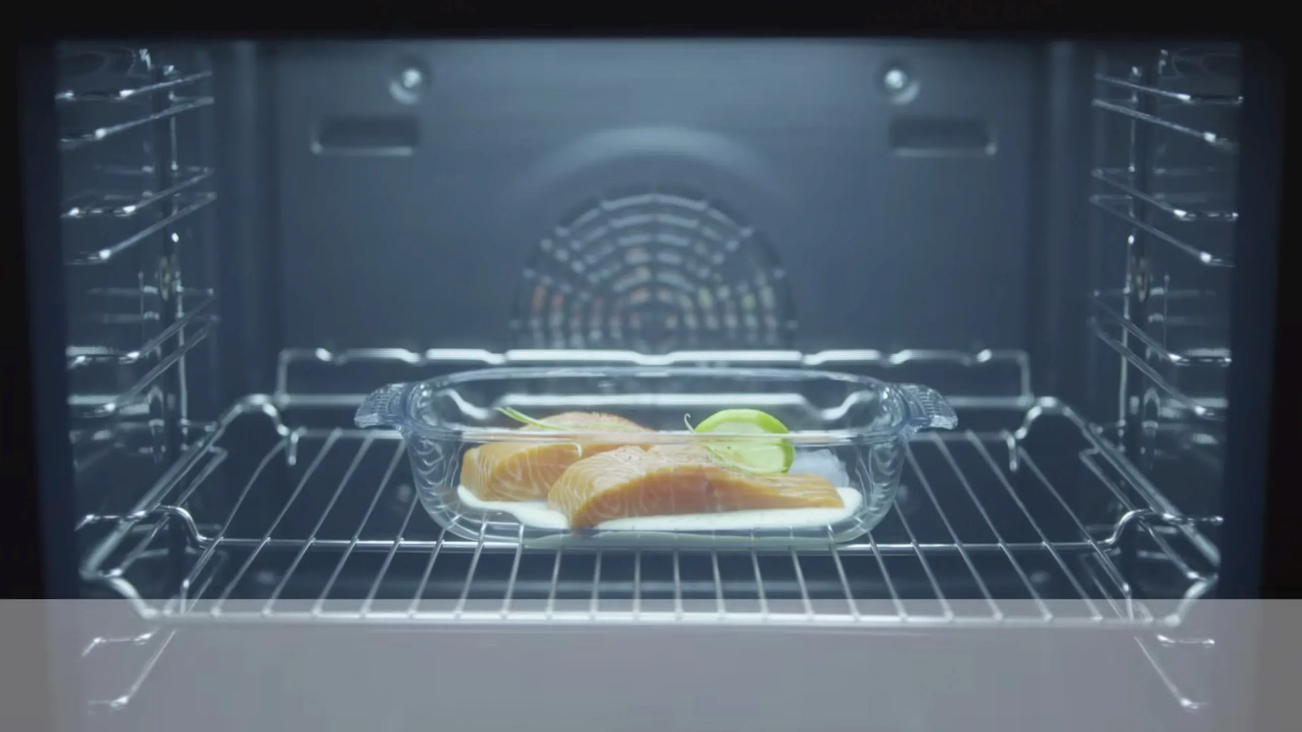 Lachsfilets in einer Glasform auf dem Rost im beleuchteten Innenraum eines Bosch Backofens mit Heißluftfunktion.
