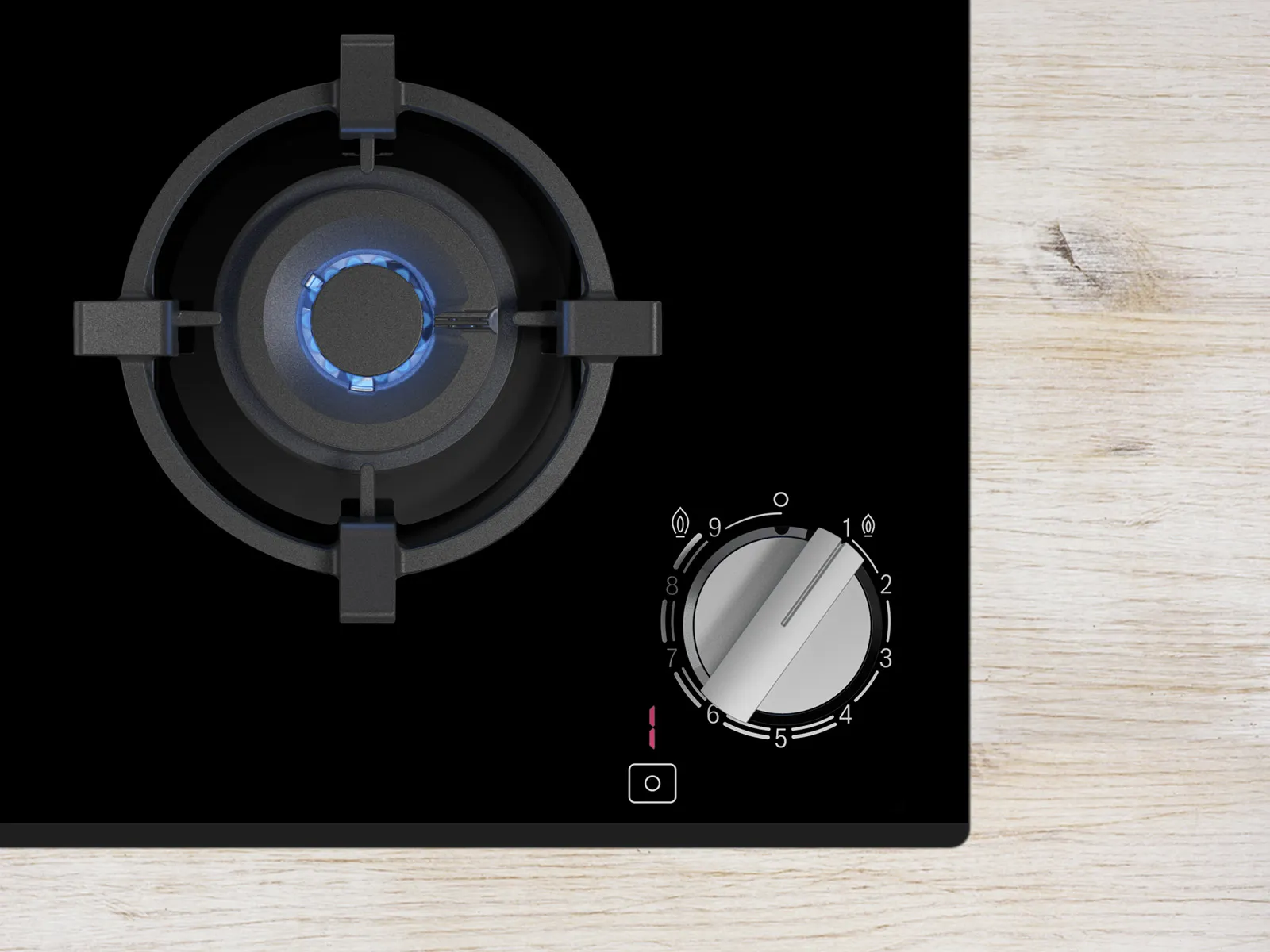 Close-up of a gas stove with a lit burner and control knob, set against a light wooden surface.