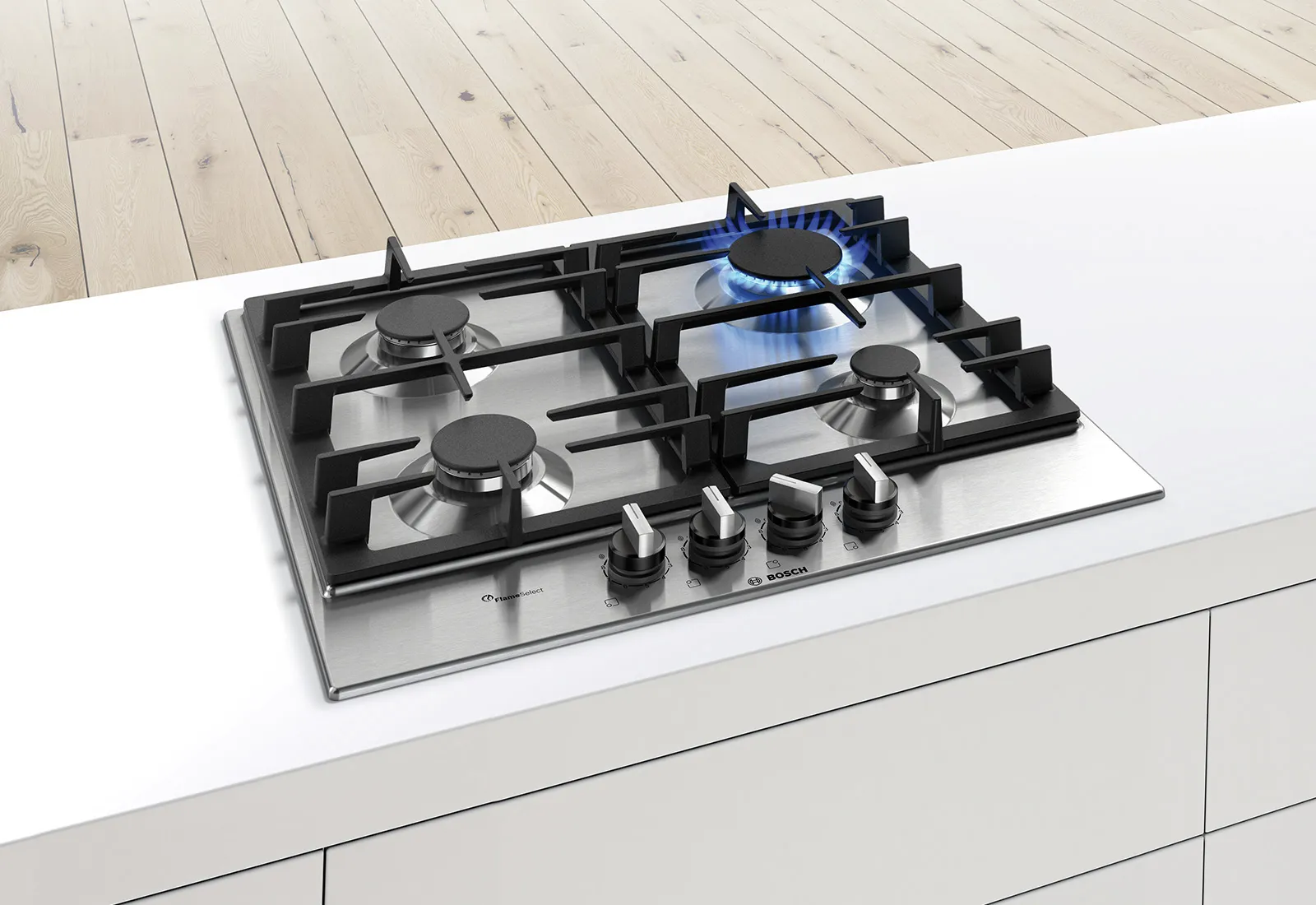 A stainless steel gas cooktop with five burners, one ignited with blue flames, set on white countertop over wooden flooring. 